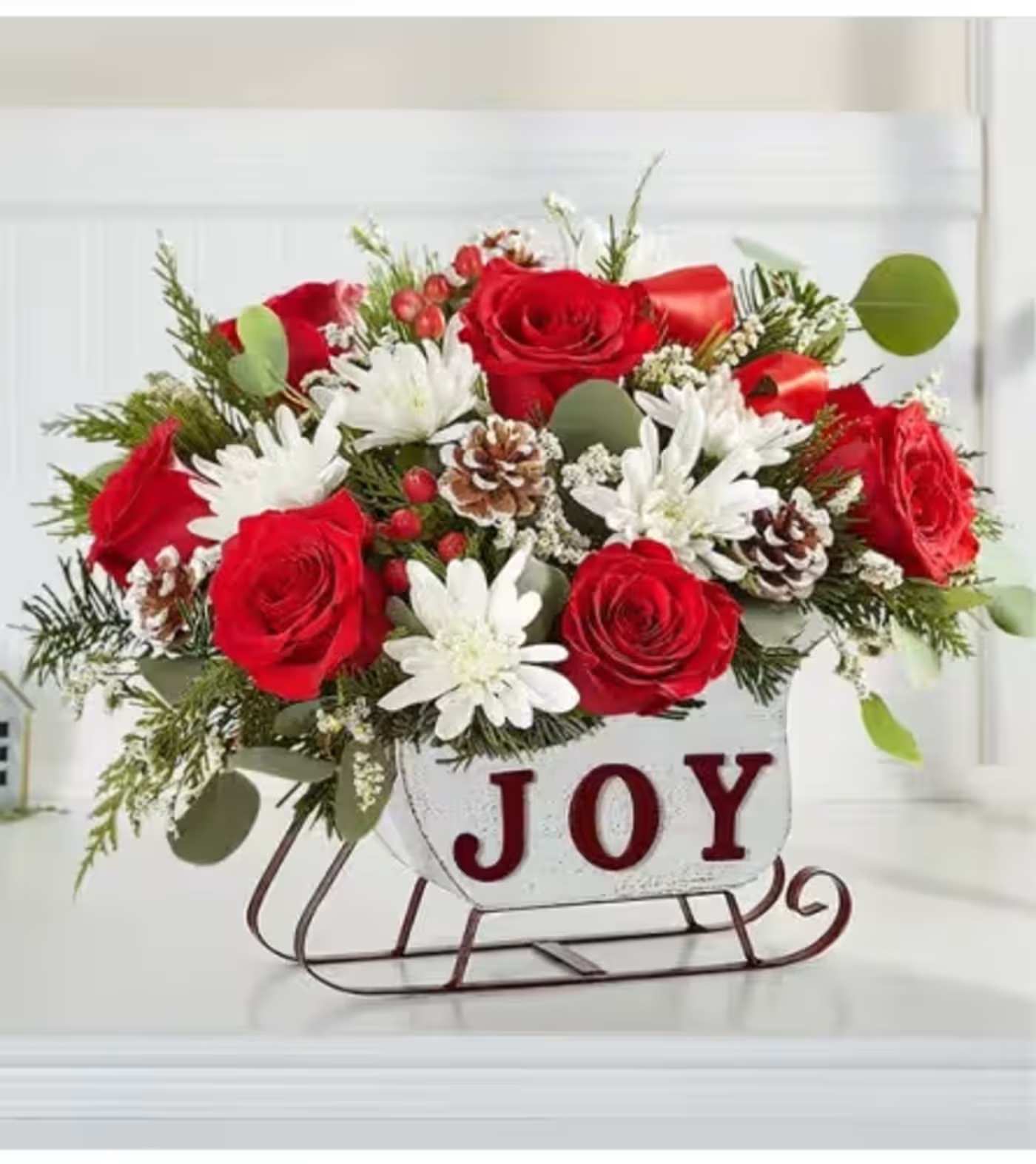 Dashing Through the Snow Sleigh - Send happiness their way with our dashing holiday sleigh! Filled with red &amp; white blooms, fragrant evergreens and pinecones, this merry arrangement is gathered in our Joyful Winter Sleigh™, a rustic, whitewashed design with vintage style messaging. Standard as shown.