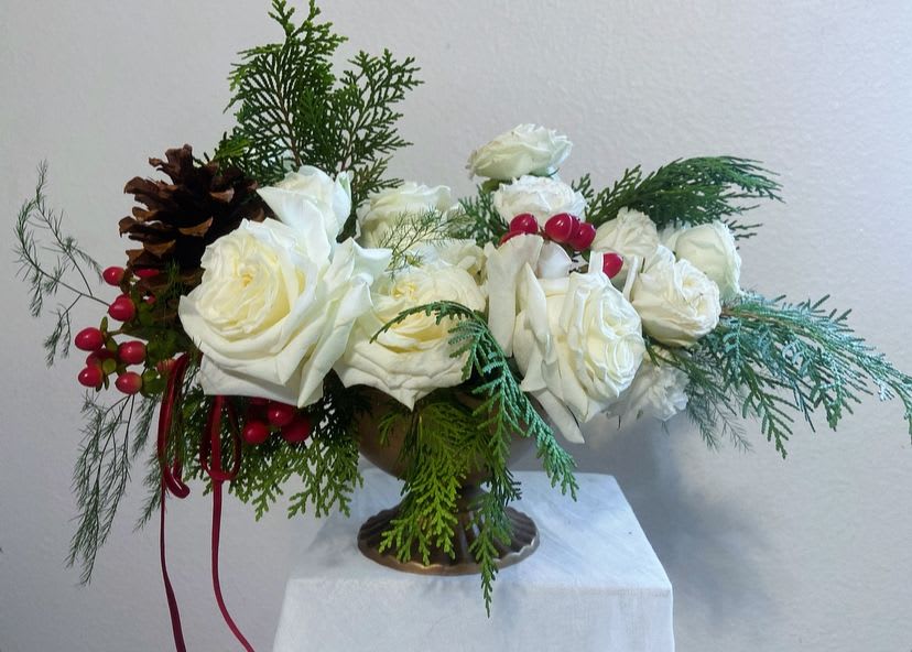 Noel - Noel is a celebration of quiet winter elegance—an artful blend of creamy white roses, fragrant evergreens, and bright winter berries gathered into a warm gold compote for a timeless, couture finish. A single pinecone adds a rustic, storybook touch, while cascading cedar and wispy textures create soft movement and a naturally draped silhouette.  Designed for holiday tables, intimate gatherings, or as a refined seasonal gift, Noel embodies the beauty of December: serene, enchanting, and effortlessly luxurious. Each piece is crafted with Italy-inspired form, lush dimension, and the signature April May Flowers attention to detail.  A statement of peace, purity, and winter romance—Noel is Christmas, reimagined.