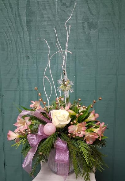 Lavender Ice - Lavender Ice Chill your holiday season with the cool elegance of Lavender Ice, a soft and serene winter arrangement designed to bring a touch of frosted magic to any space. Lush seasonal blooms in shades of lavender, icy white, and silvery accents are artfully arranged to create a soothing, wintry palette. Nestled among the flowers is a beautiful ornament keepsake — a charming touch your recipient can treasure long after the flowers have faded. Perfect for gifting or adding a peaceful winter glow to your home.