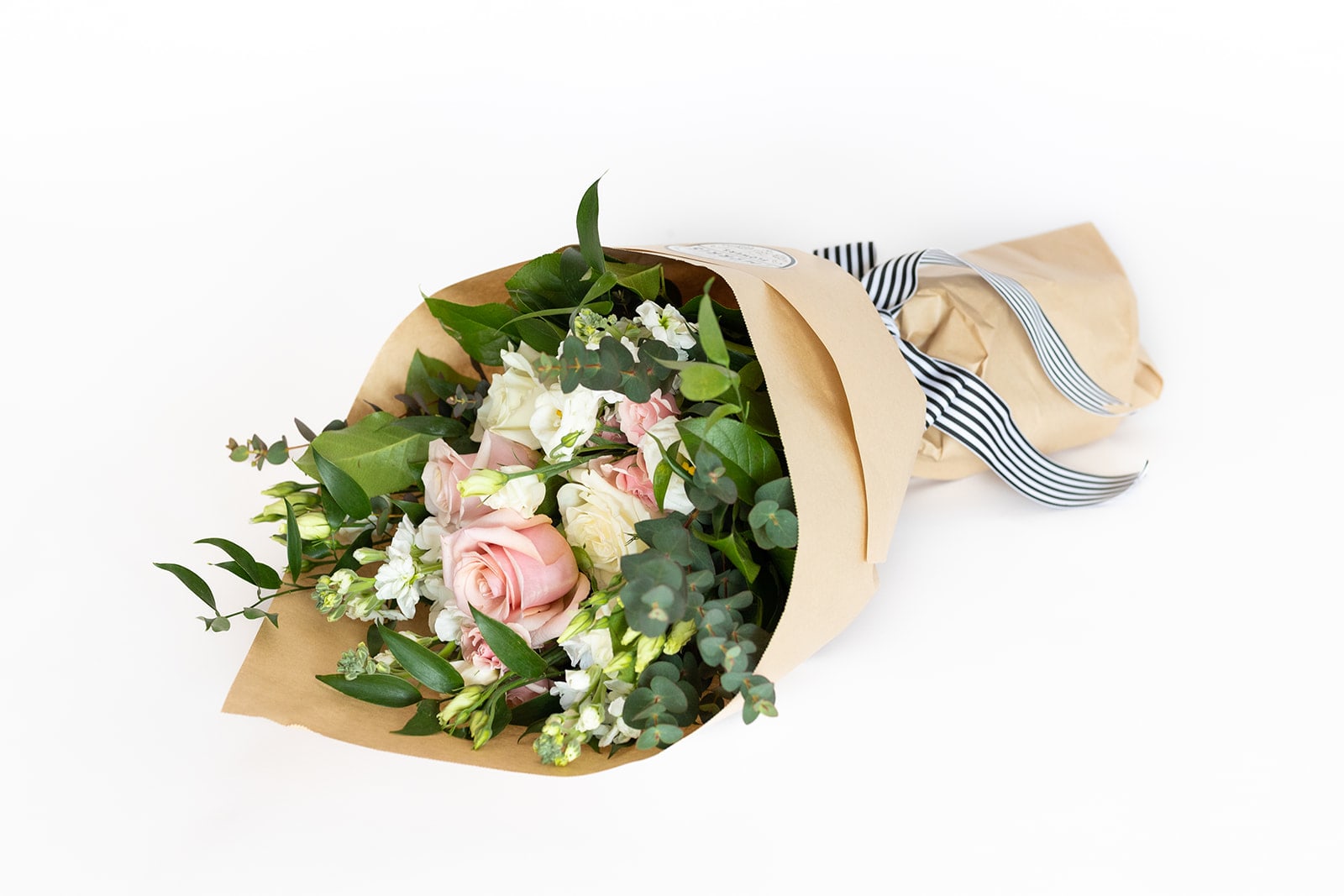 Blush Collection - Wrapped Bouquet  - Soft shades of pink, peach, and ivory—reminiscent of a vintage English garden—come together in our Blush Collection. This arrangement features peach "Shimmer" garden roses, soft pink roses, white Lisianthus, and crisp white hydrangea, accented with Italian Ruscus and Eucalyptus greenery.  A hand-tied bouquet of fresh cut blooms and greenery designed and ready for a favorite vase. Perfect for a thank you gift, get well wish, Anniversary, birthday or hostess/host gift.   Product Details: Wrapped bouquets are 18" long and 12" wide, wrapped in paper and tied with ribbon. The bouquet has a water source inside to keep it fresh for delivery. 