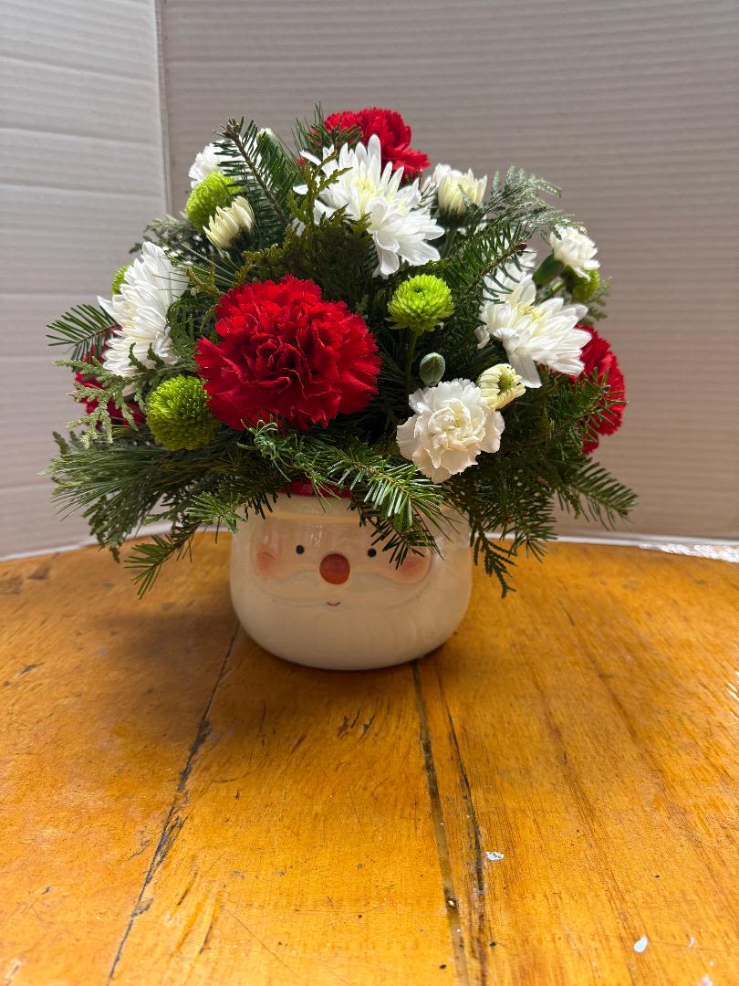 Santa Face - Ceramic Santa Face container filled with various Christmas greens, red carnations, green button poms, white mini carnations and white cushion poms