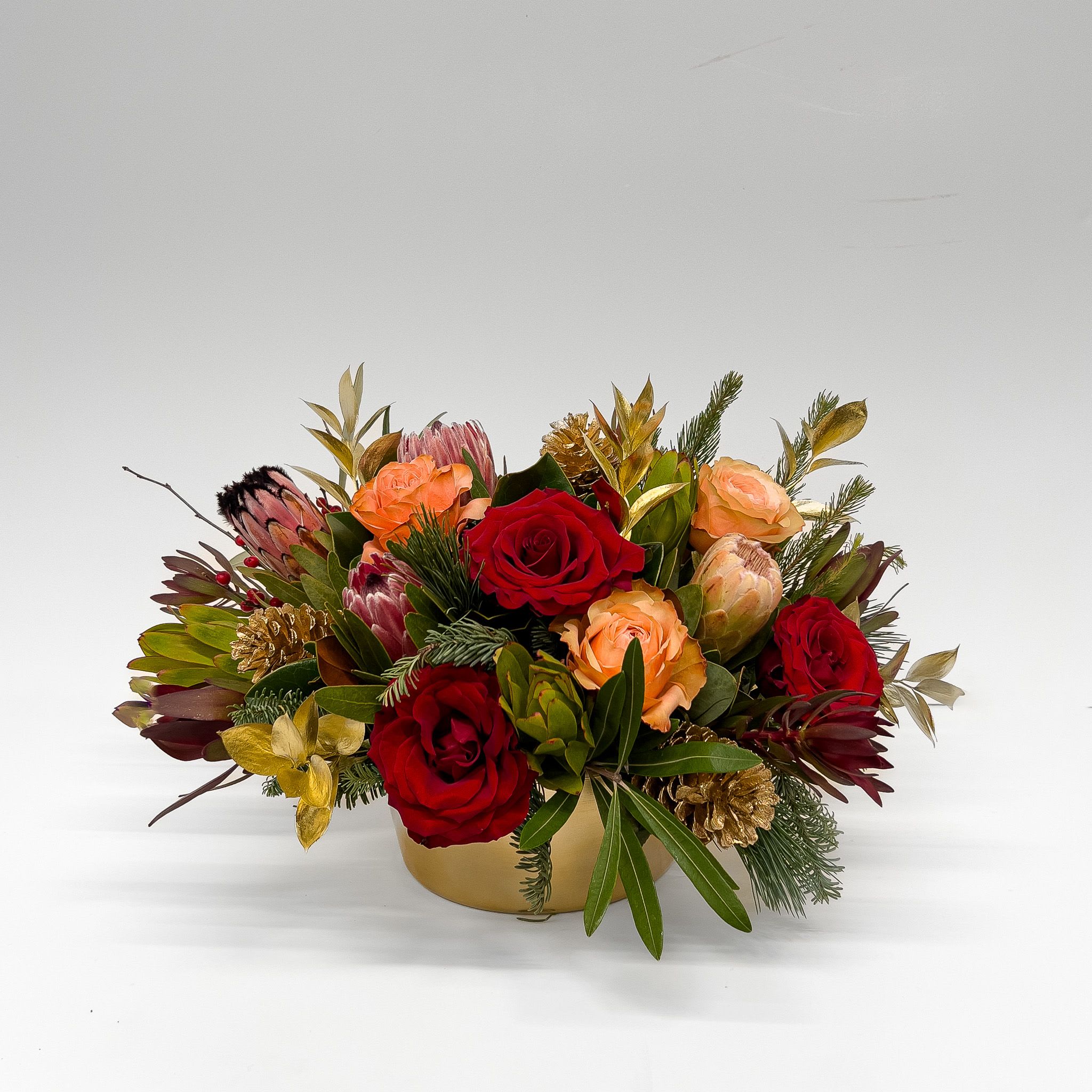 Holiday Glow - Classic holiday elements come together around sculptural protea that adds texture and character. It’s a fresh take on tradition, familiar holiday charm with a touch of global flair.