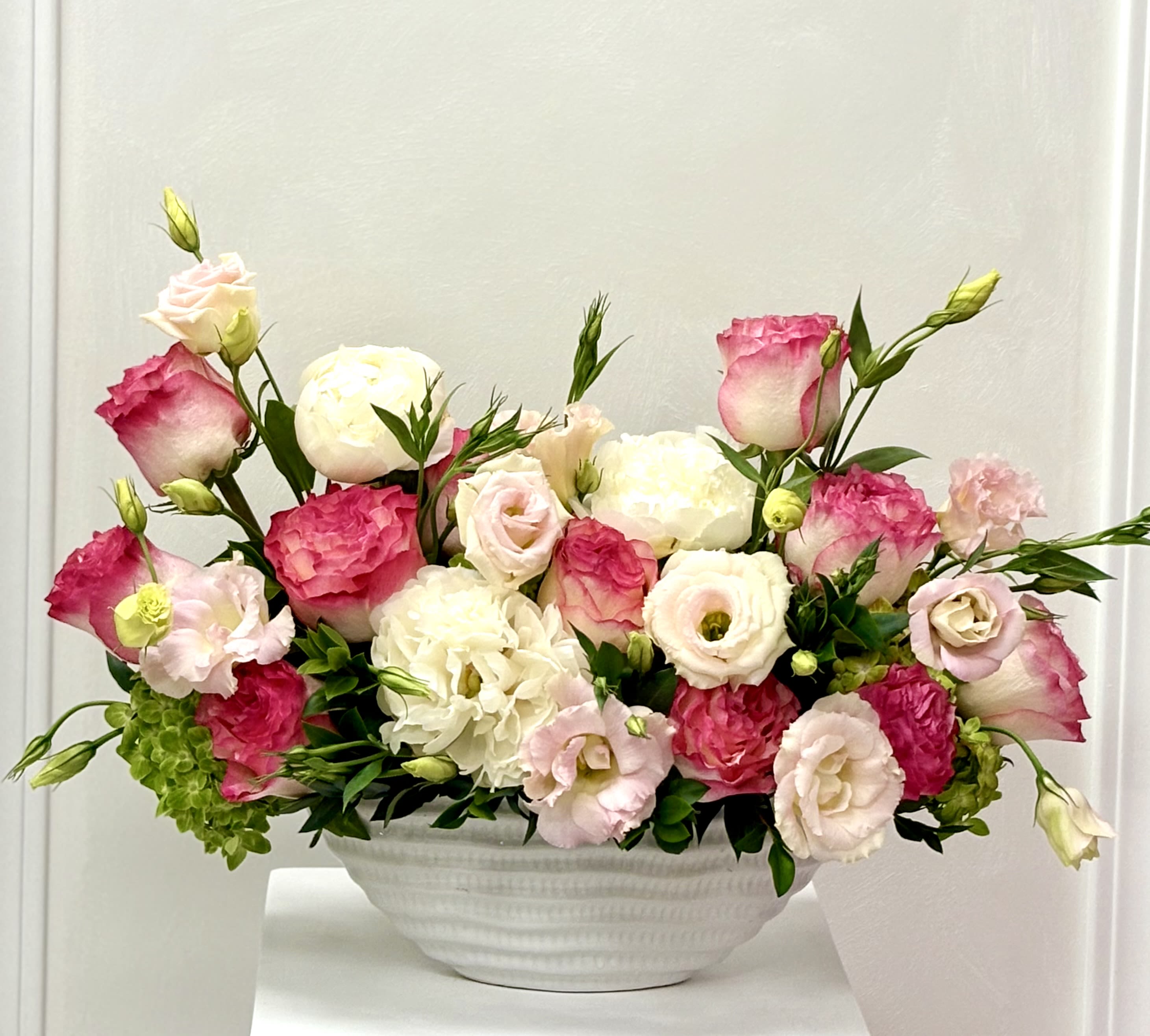Grace in Bloom By VLM Flowers - Delicate, balanced, and full of life — Grace in Bloom is a celebration of natural beauty. Blushing roses, lisianthus , and soft peonies mingle effortlessly in a classic white bowl, creating a piece that embodies poise and serenity.