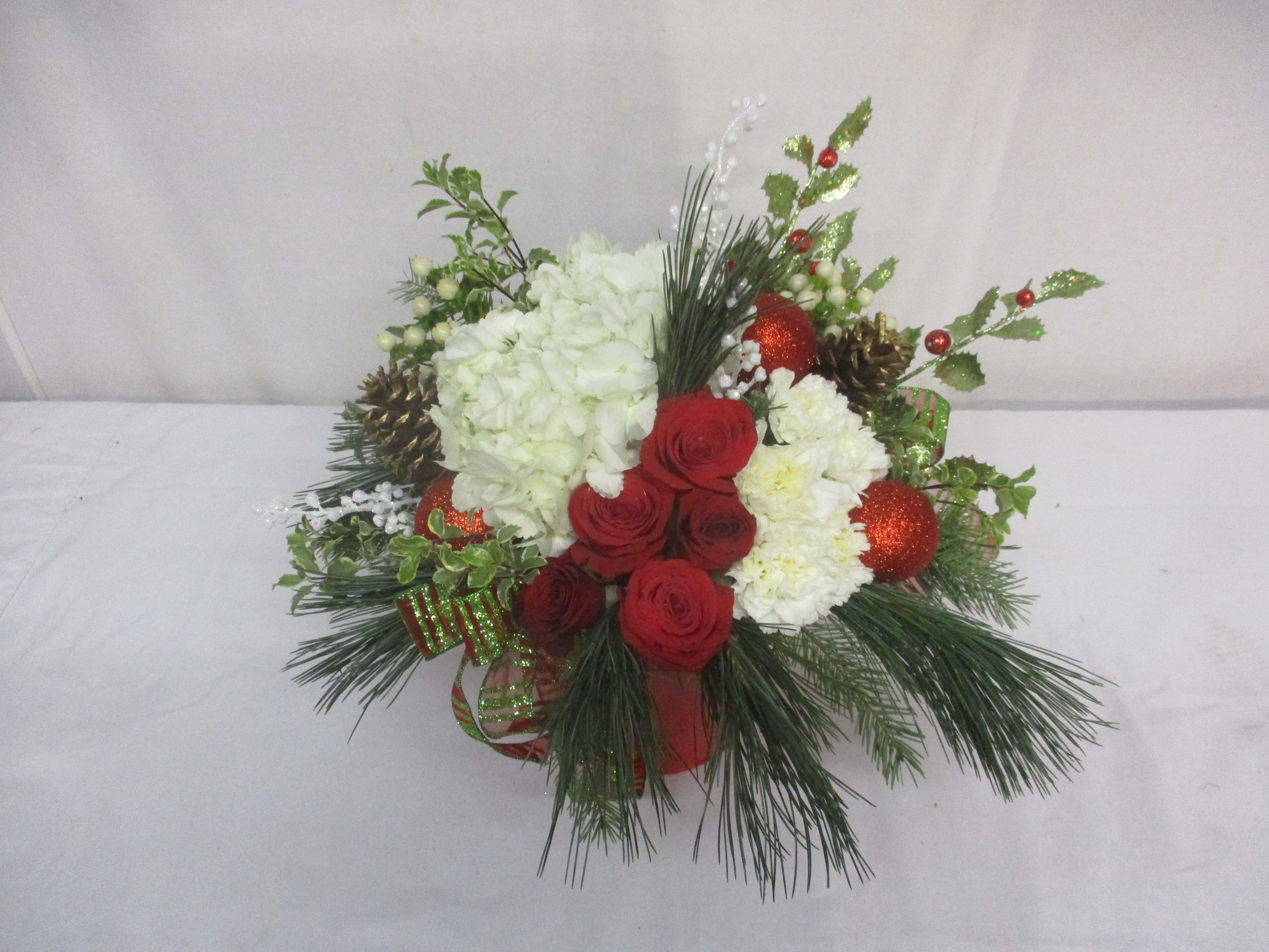 Christmas Glee - A beautiful mix of Christmas flowers and colors come together to create a stunning arrangement to impress the most discerning recipient.