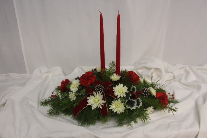 Christmas Traditions - A beautiful Christmas centerpiece to adorn any table for the holidays.  Red taper candles  are surrounded by a bed of pine and traditional red carnations and white poms, accented with ribbons, cones and silk holly.