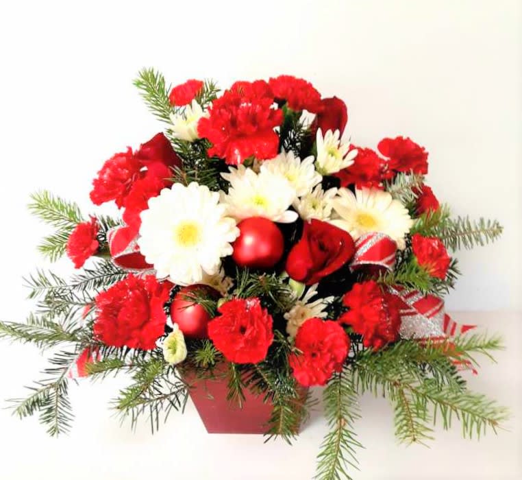 Happy Christmas - Just the right gift for a happy Christmas wish with carnations,mums,ribbon and holiday greenery in an all around centerpiece style.