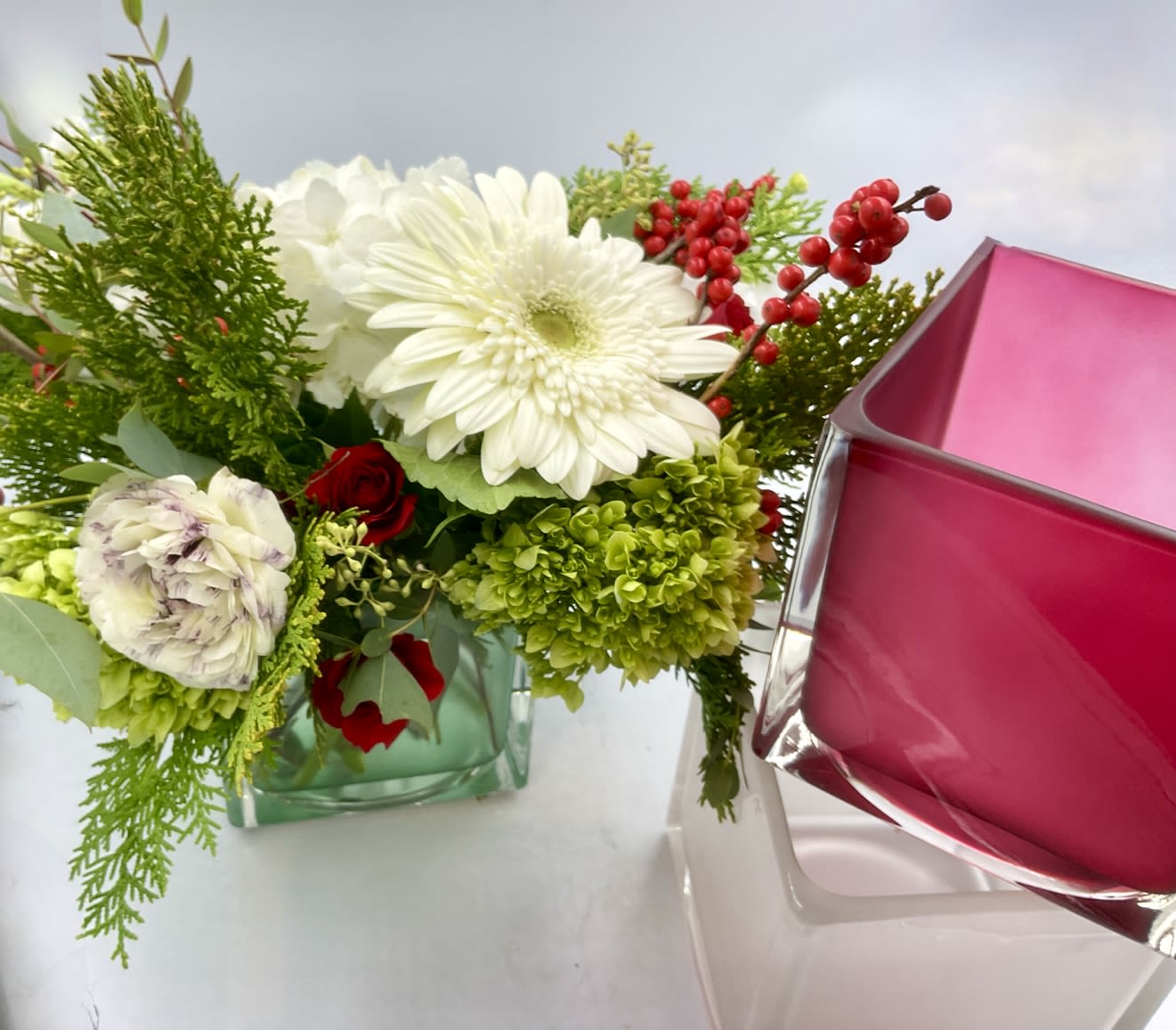 The Festive &amp; Frosty (In Single Duo or Trio!) - We ordered these vases not realizing how fun and beautiful they really would be!  They come in frosted glass white, a muted subtle red and a subtle green.  Vases are super sturdy 6x6 cubes in which we design the flowers super lush and way beyond the 6x6 size.  Perfect for a kitchen, dining or coffee table, these vases are filled with a premium holiday mix like hydrangea, roses, .   We can design them in any holiday color - For X was it a mix of reds, greens whites and possible some metallics. Hanakuh we use blues, greens whites and silvers. Please indicate in the notes your preferences for vase color and holiday palette.   Standard size is 1x vase any color Deluxe is a Duo any two colors Premium is a trip and 3 colors  Please indicate.  You will LOVE these!! We use premium flowers for these arrangements like hydrangea, matcha roses, ranunculus, tulips, gerbs.  