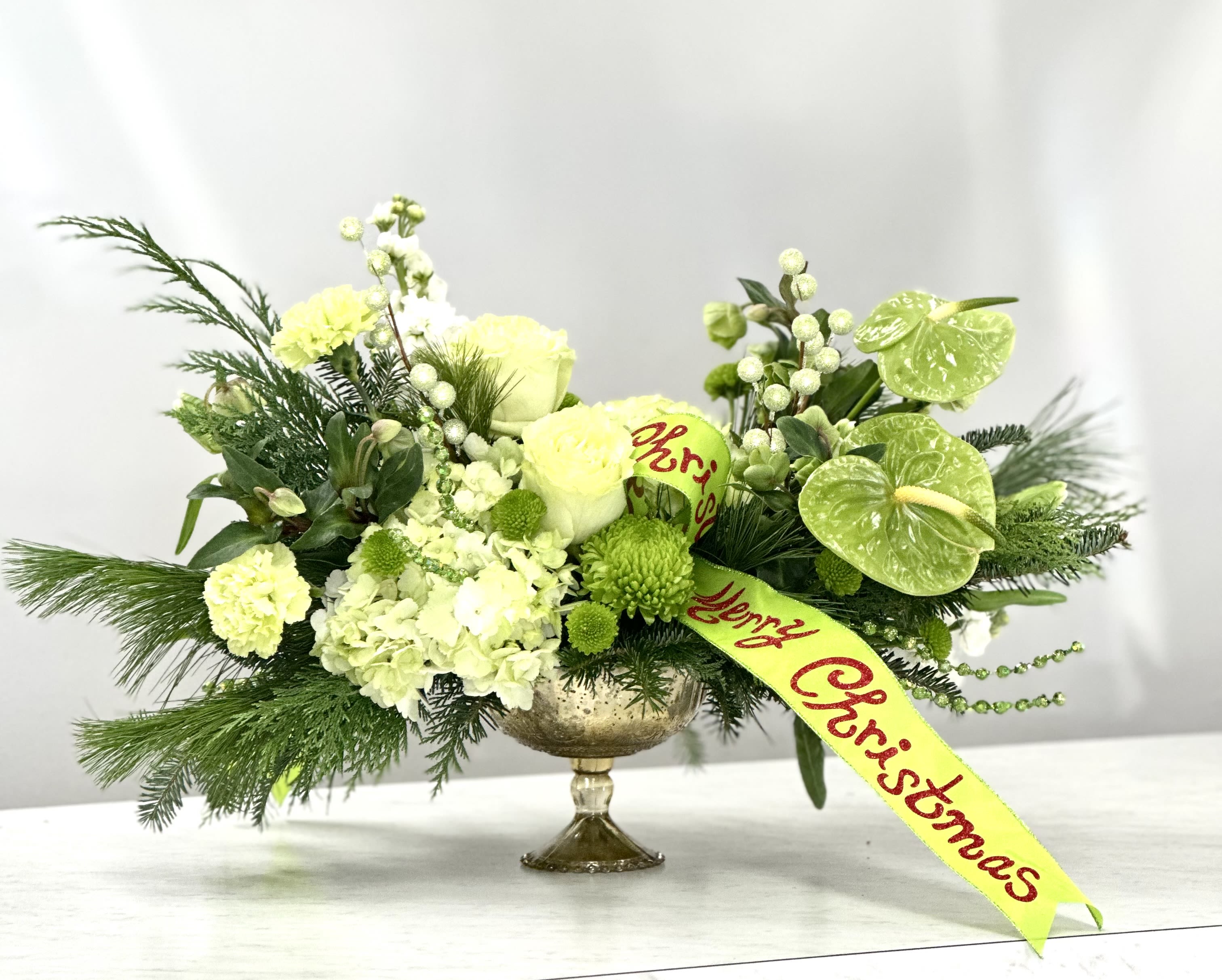 Mrs. Grinchmas - Impress your guests with Mrs. Grinchmas, an elegant floral centerpiece featuring green tulips, hellebore, green anthurium, and beautiful green garden roses.