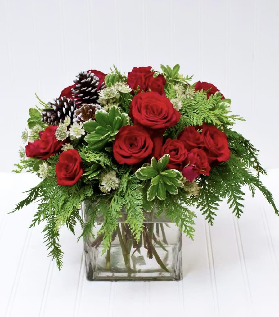 Merry Moments Cube Arrangement - Celebrate the season with our Merry Moments Cube Arrangement, a charming mix of assorted Christmas greenery and festive florals arranged in a modern cube vase. Rich textures, fresh seasonal scents, and warm holiday colors come together to create a joyful piece perfect for any home or office. Compact yet full of spirit, it’s an ideal gift or décor accent for bringing Christmas charm to any space.