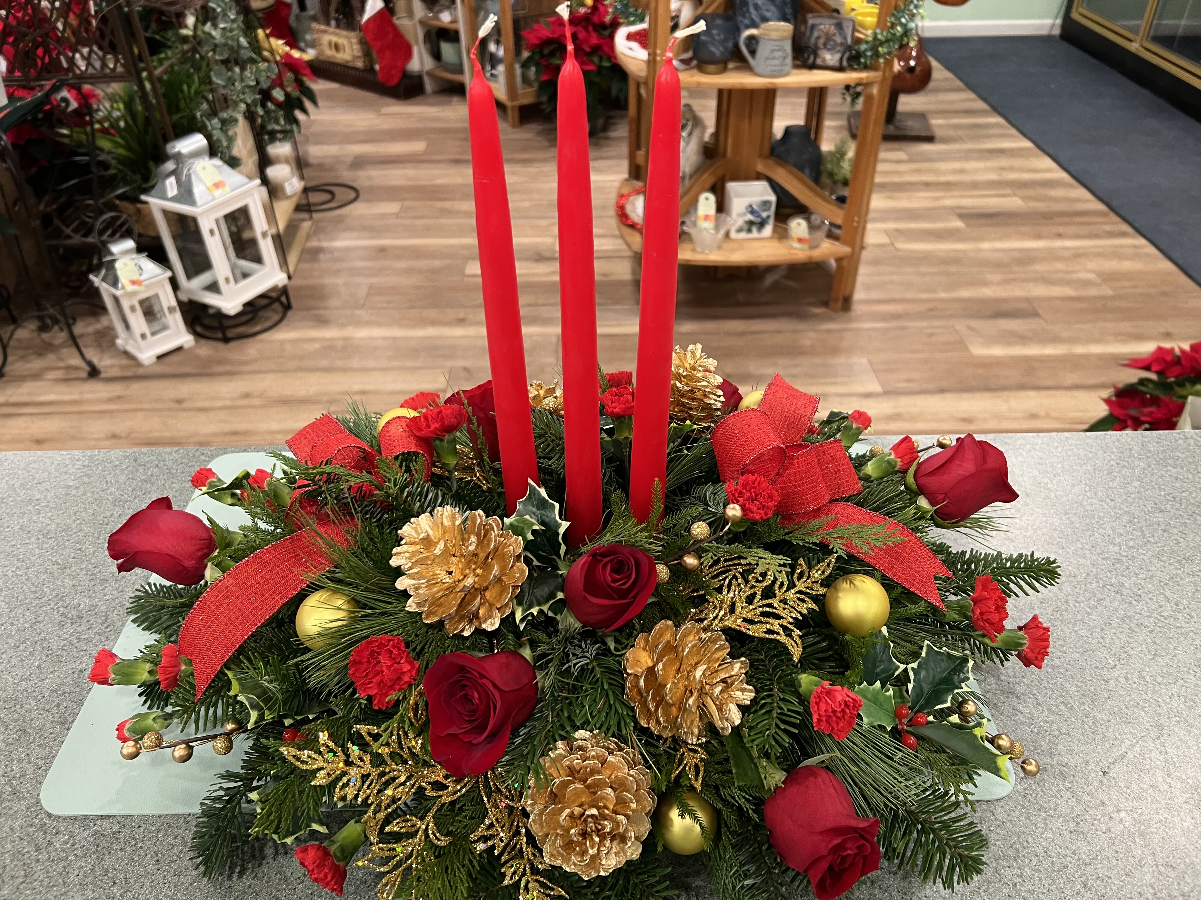 Christmas Spirit Centerpiece (CSC) - The spirit of the season is captured in this centerpiece including red roses, mini carnations, pinecones and other festive trim for the season.
