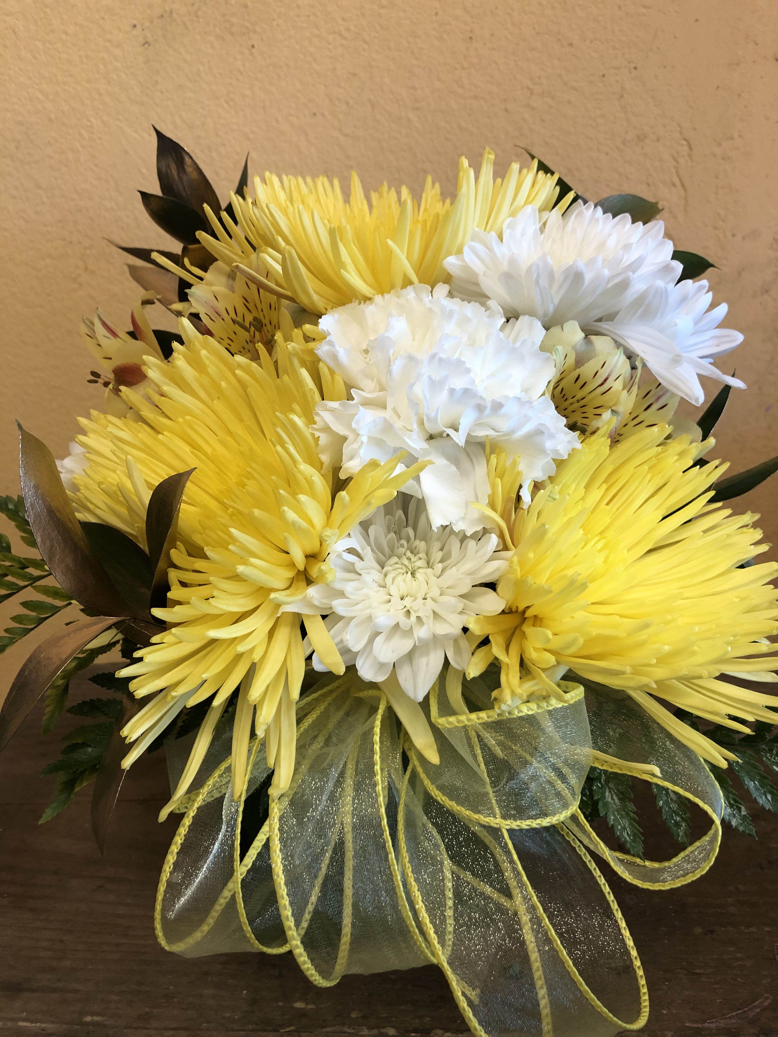 YELLOW AND WHITE CUBE (DESIGNER CHOICE) - THIS IS A CUBE ARRANGEMENT WITH YELLOW AND WHITE FLOWERS TO INCLUDE CARNATIONS, CUSHION, ALSTROMERIA AND SPIDERS.   FILLERS WILL BE EITHER GOLD OR SILVER RUSCUS. NOTE THIS ARRANGEMENT DOES NOT INCLUDE ROSES OF LILIES.  DELUXE AND PREMIUM PRICE WILL ONLY INCLUDE MORE OF THE MENTION FLOWER BUT IT WILL NOT INCLUDE ROSES OR LILIES