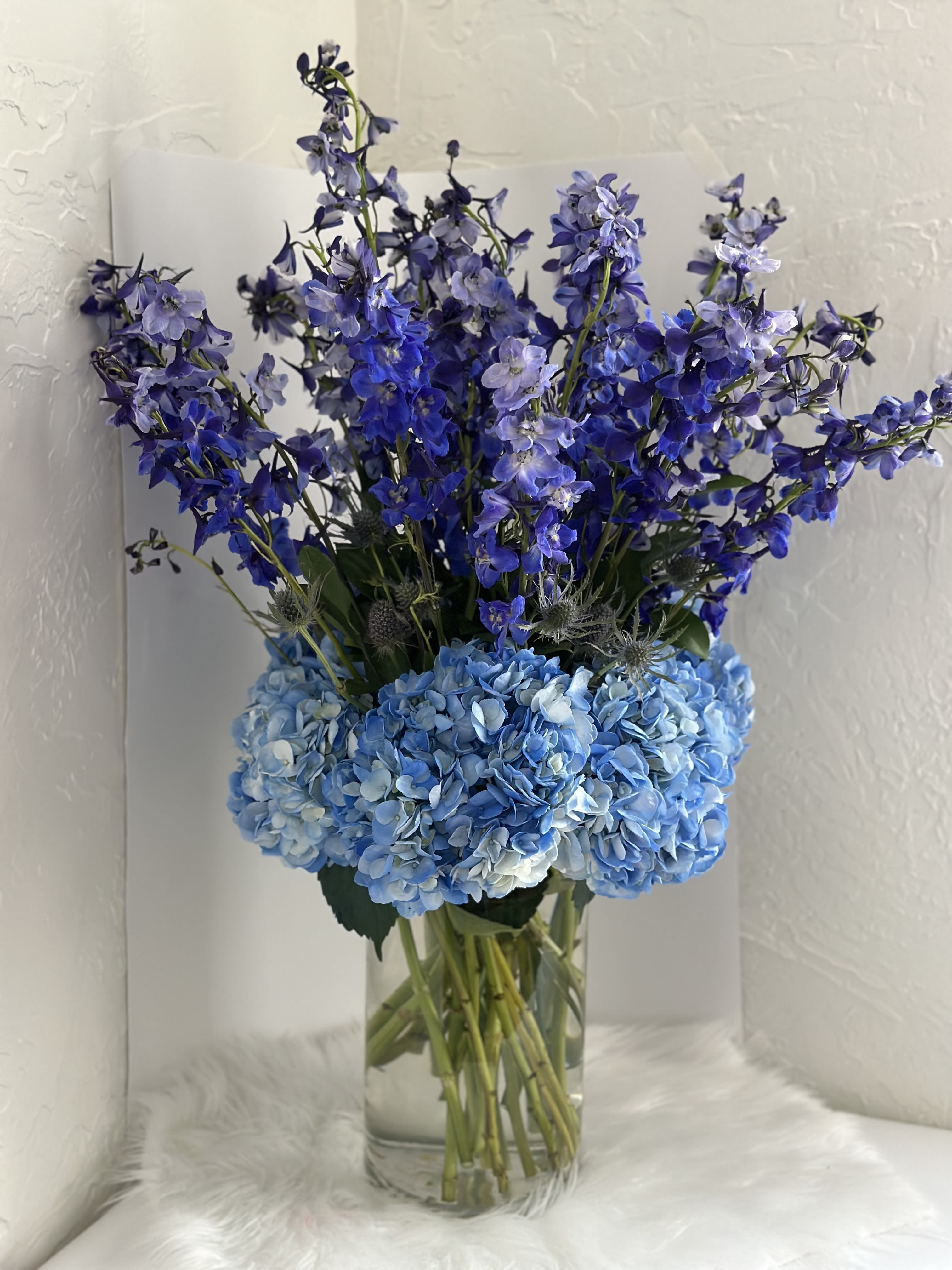 Blue Addiction - Bring home this beautiful arrangement of blue delphinium and blue hydrangeas to impress your guests and light up a room