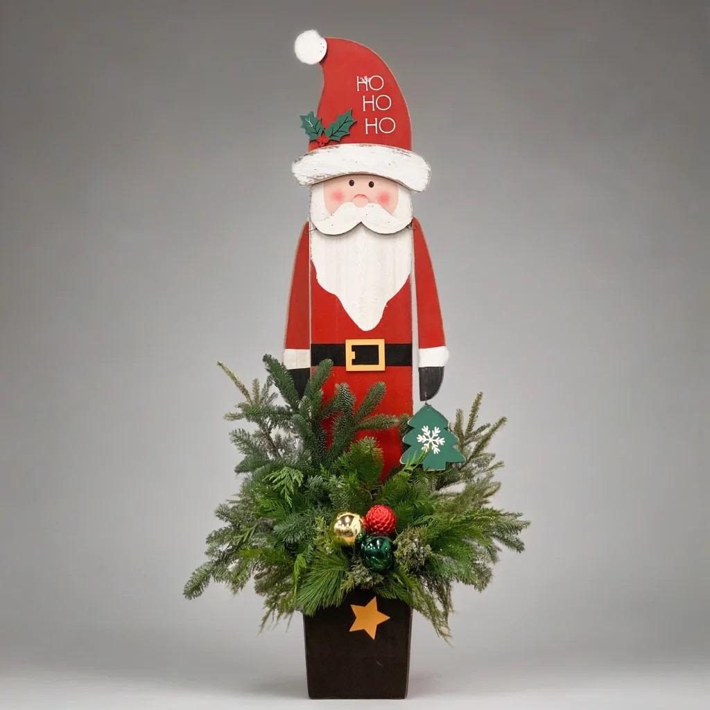 Tall Santa Patio Pot - 4 FT WOOD CUTOUT SANTA PATIO POT WITH FRESH EVERGREENS  Bring instant holiday charm to your front porch, patio, or entryway with this handcrafted 4 ft Wood Cutout Santa Patio Pot. This festive outdoor arrangement features a tall, rustic wood Santa standing above a lush blend of fresh winter evergreens. At 4 feet tall and 22 inches wide, it makes a beautiful statement piece for greeting guests all season long.  The wood Santa is fully removable after the holidays, allowing the sturdy wooden planter box and evergreen arrangement to stay outdoors throughout the winter. Keep the greenery for natural seasonal décor, then easily add your own accents as the months change.  Perfect for porches, patios, storefronts, and holiday displays. A great choice for anyone searching for outdoor Christmas décor, winter porch pots, fresh evergreen arrangements, or festive front-door decorations.  KEY FEATURES • 4 feet tall x 22 inches wide • Handcrafted wood cutout Santa • Fresh mixed winter evergreens • Suitable for outdoor use all season • Santa can be removed after Christmas so the pot can remain out all winter • Ideal for porch décor, patio décor, and outdoor holiday decorations 