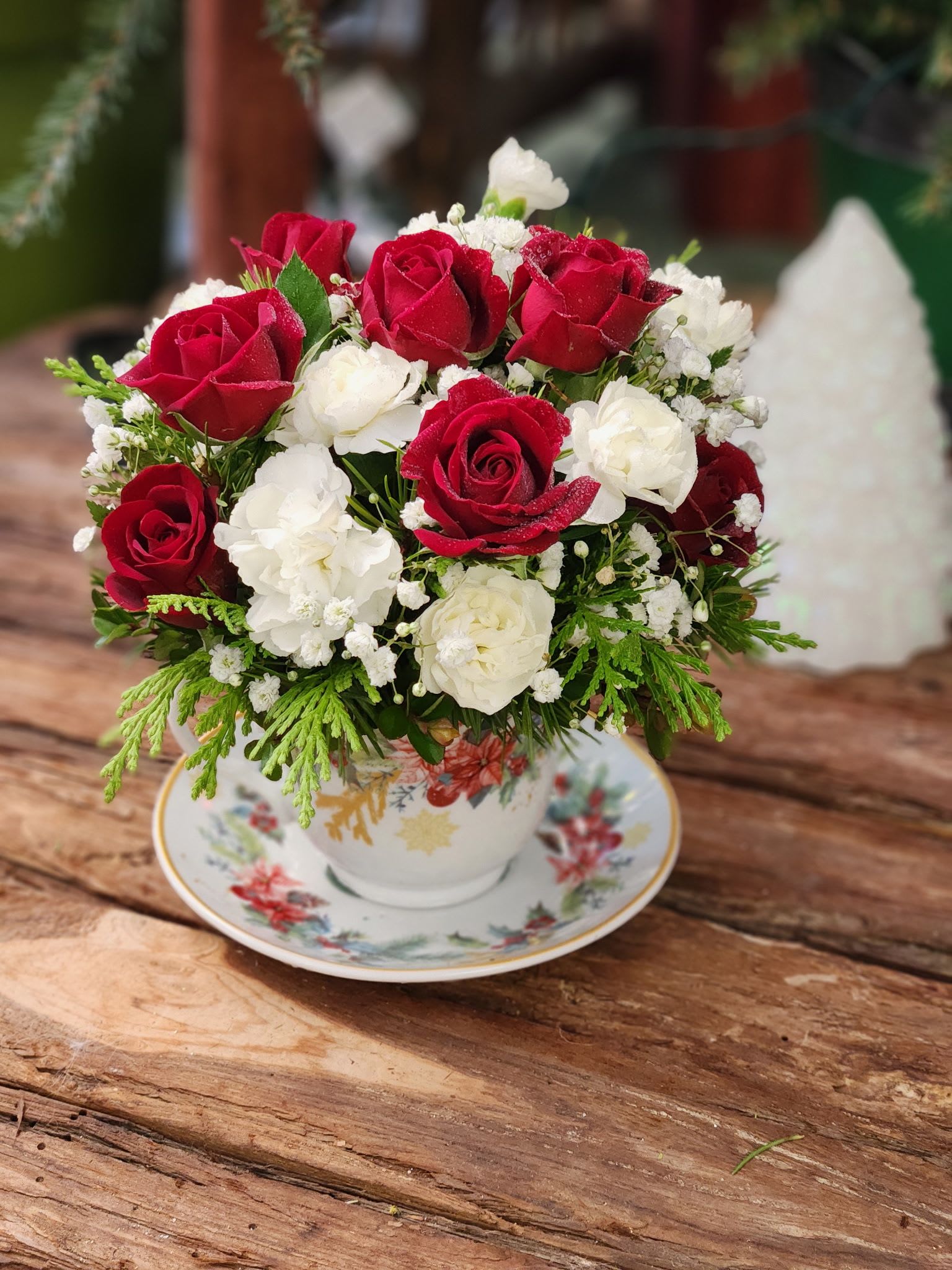 A Cup of Cheer - Celebrate the season with A Cup of Cheer, our festive Christmas tea cup flower arrangement designed to spread warmth and holiday joy. This charming holiday mini arrangement is created in a collectible teacup and filled with fresh, seasonal blooms in classic winter tones—perfect for adding a touch of Christmas spirit to any home or office.