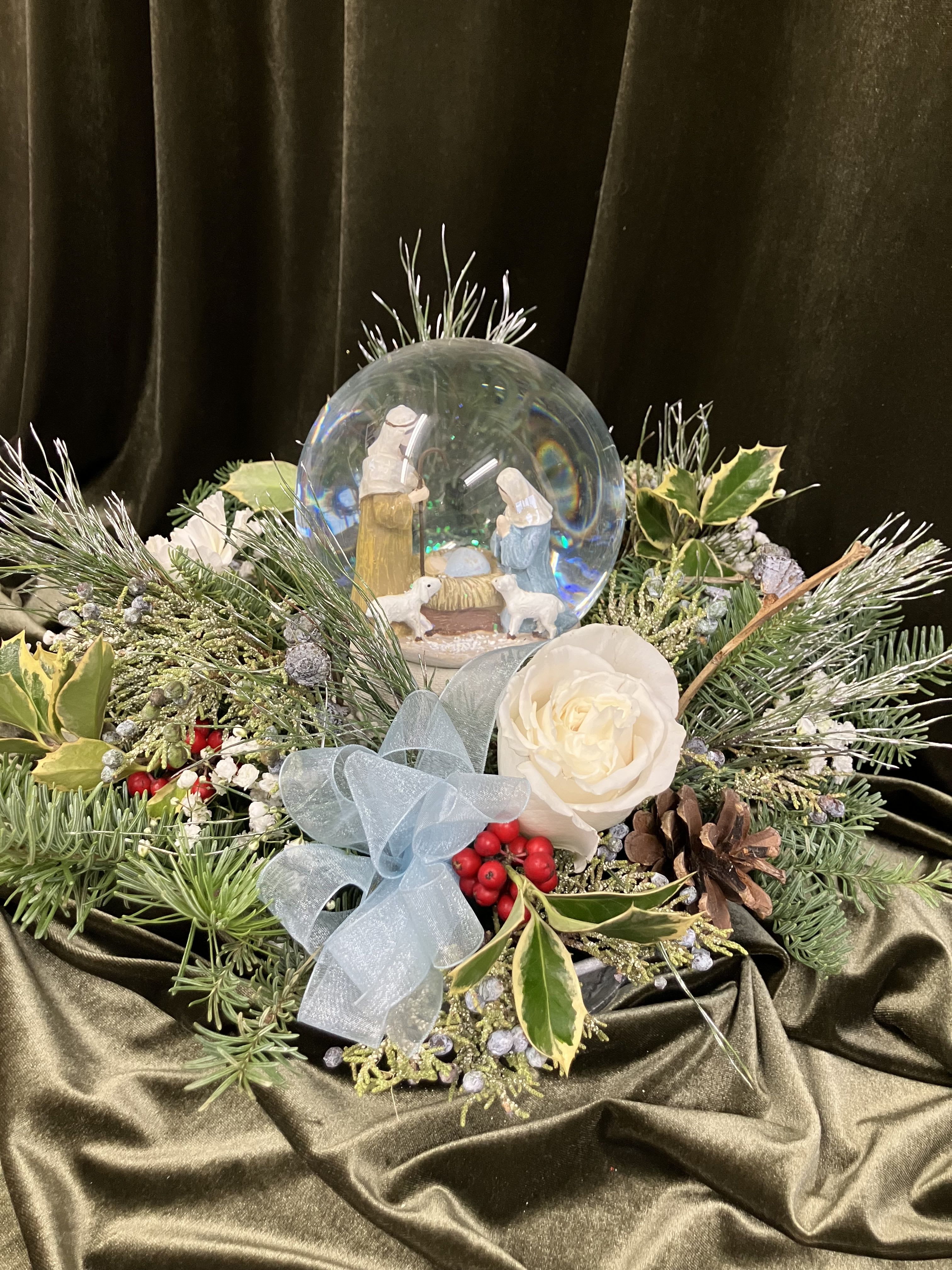 Snow Globe and Flowers - Sweet baby Jesus scene snow globe and music box surrounded with greens and white flowers. 