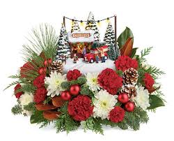 Thomas Kinkade's Family Tree Boquet - his holiday season, celebrate the heroes among us! Set atop a magnificent bouquet of festive roses and fresh Christmas greens, this hand-painted, light-up Thomas Kinkade sculpture. This charming gift features red carnations, white chrysanthemums red miniature carnations, oregonia &amp; noble fir.