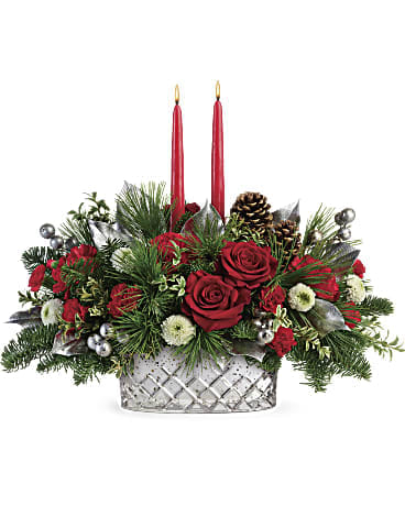 Merry Mercury Centerpiece - Brimming with festive Christmas red roses and lit by two glowing tapers, this gorgeous crosscut mercury glass bowl is a magical centerpiece and keepsake gift they'll enjoy year after year! Red roses, red carnations, red miniature carnations, and white button spray chrysanthemums are accented with noble fir, white pine, oregonia, lemon leaf, and red candles. Delivered in a Merry Mercury Bowl. Approximately 18" W x 15" H 