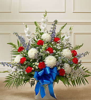 Patriotic Tribute Floor Basket Arrangement -   Capture all the love, respect and honor a beloved veteran deserves with this patriotic sympathy arrangement. Crafted from the finest white football mums, red carnations, blue delphinium and more, it is a beautiful expression of your sympathy and devotion to a departed hero. Floor basket arrangement of fresh white football mums, red carnations, blue delphinium and more Appropriate for family, friends or business associates to send directly to the funeral home Our florists use only the freshest flowers available, so colors and varieties may vary Measures approximately 32"H x 38"L