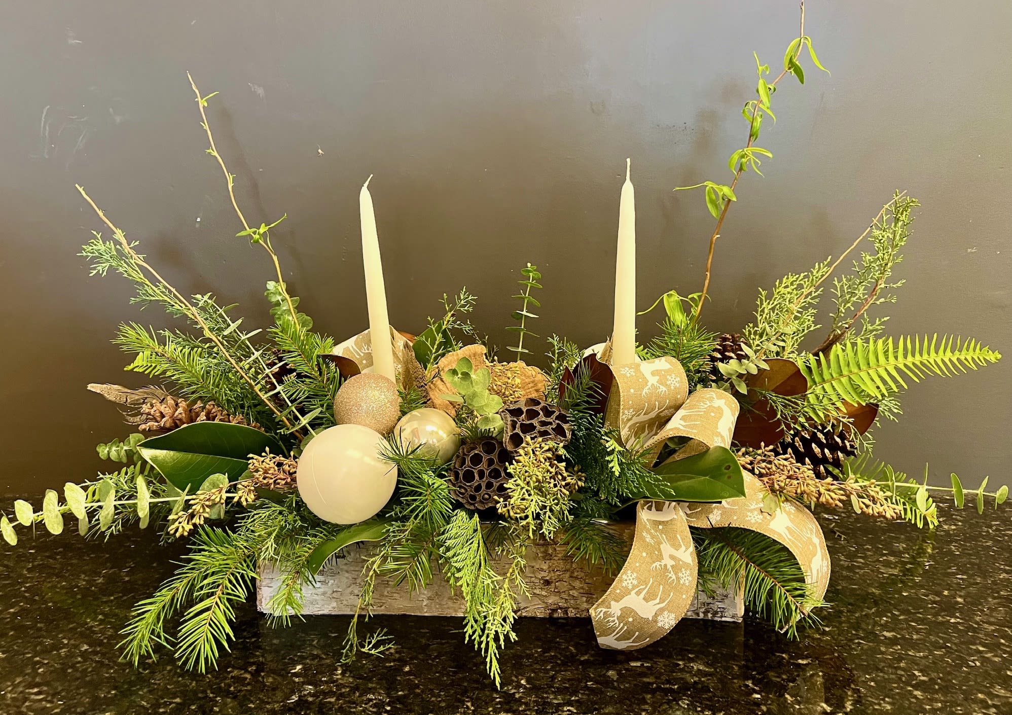 Sleigh Ride - Designed in a birch lined metal tray, this festive holiday centerpiece will last weeks to come. It features a wide variety of christmas and winter greens, dried lotus pods and mushrooms and is also accented with ribbon and decorative ornaments. Light the dripless candles to celebrate the season. 