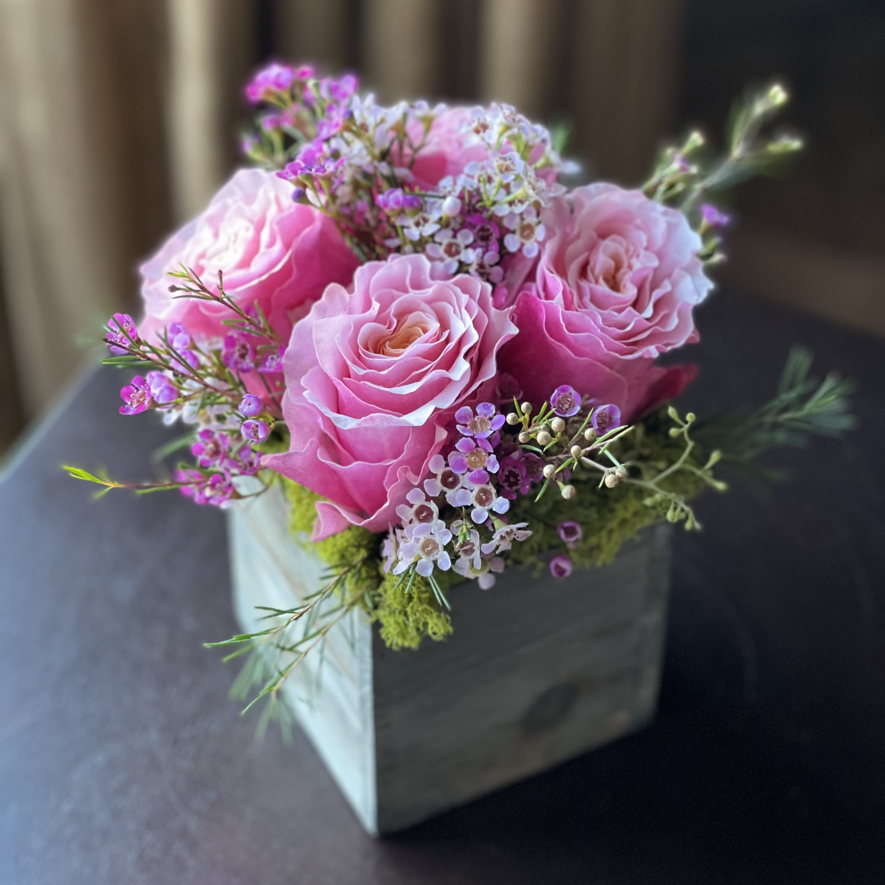 Petite Blush - Blushing pink Roses accented by dainty pink and white Waxflower blooms and nestled above lush green moss. Absolutely beautiful and right-sized for a desk, bed-side table, or kitchen counter.  