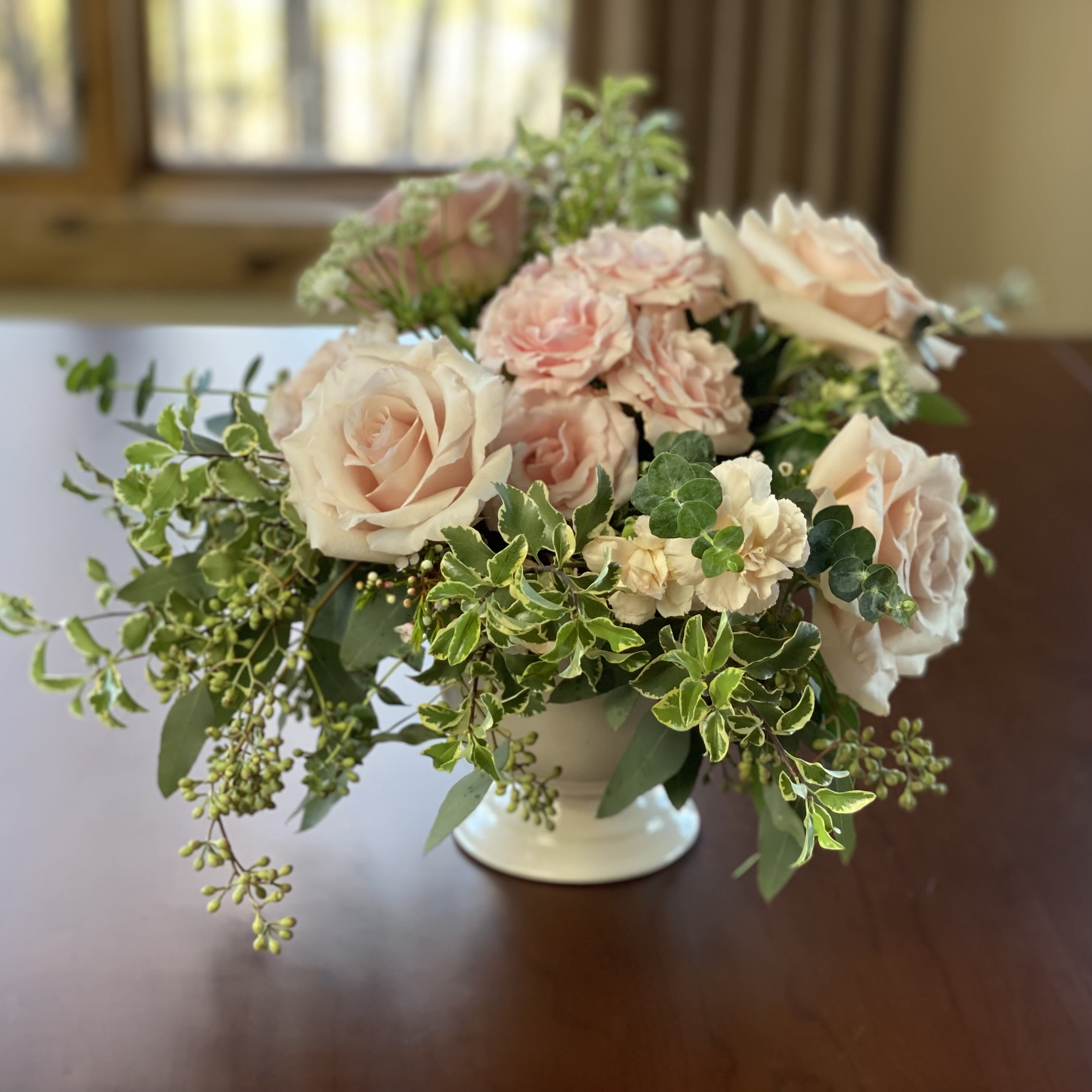 Rococo Rose - An absolutely gorgeous bouquet! Soft blushing pink hues to warm the heart. Blush pink roses and pink spray roses take centerstage in this bouquet. A romantic, asymmetrical arrangement with white astrantia, seeded eucalyptus and variegated pittosporum branches. Ceramic vase. 