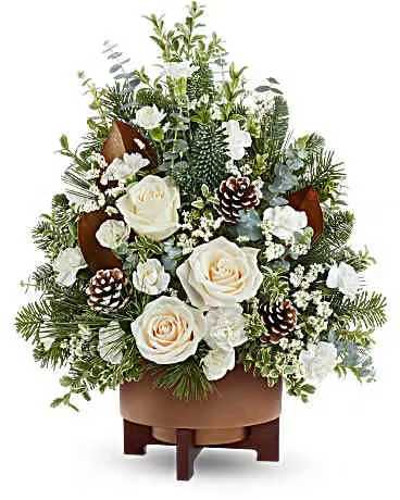 Teleflora's Alpine Snow Tree - Alpine Snow Tree glows with white roses, winter greens, and pinecones in a chic copper planter. A tranquil floral Christmas tree, perfect for seasonal gifts or adding a cozy holiday touch to your home. Alpine Snow Tree includes white roses, white miniature carnations, white limonium, spiral eucalyptus, oregonia, magnolia leaves, noble fir, and white pine-arranged in a modern copper-finished planter for winter charm.