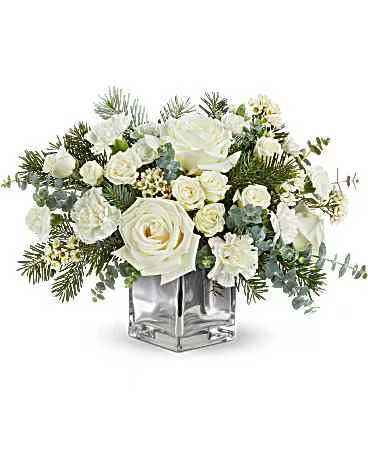 Teleflora's Arctic Blooms Bouquet - Arctic Blooms Bouquet glows with white roses, winter greens, and frosty details in a stylish silver cube. A peaceful and elegant gift or Christmas decoration for cozy seasonal gatherings. Arctic Blooms Bouquet features white roses, white spray roses, white carnations, white miniature carnations, white waxflower, spiral eucalyptus, and noble fir-arranged in a silver cube vase for winter elegance.