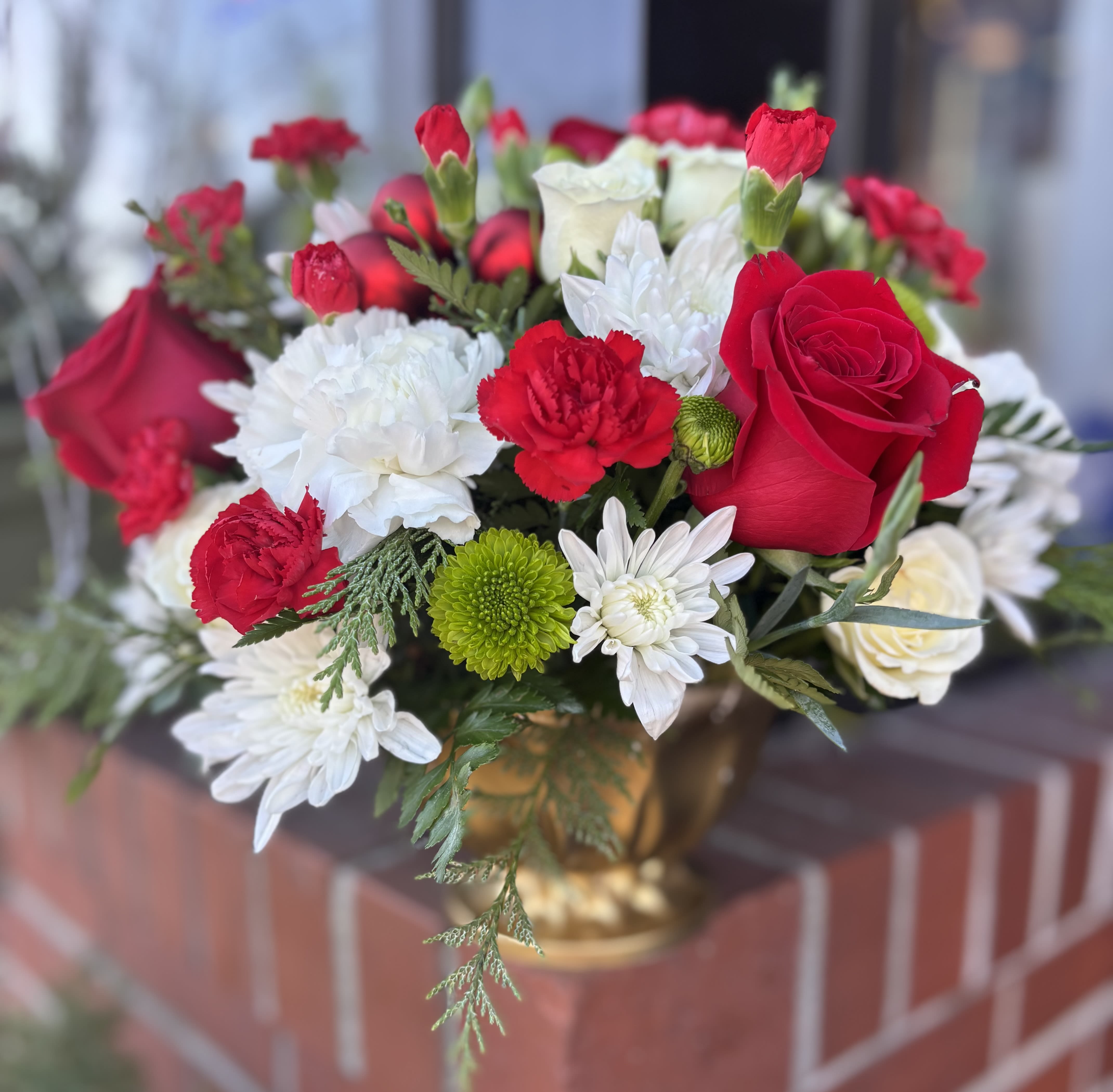 Holiday Bloom - Our selection of red, green, and white blooms with holiday details (vase type depends on availability).