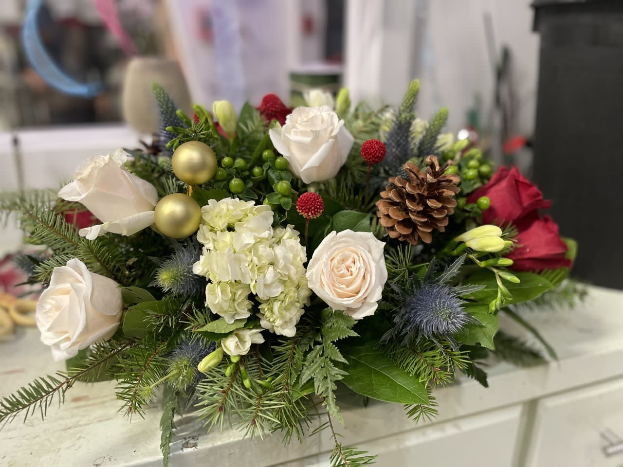 Celebration Table - Table centerpiece for 2-4 place settings - Overall about 18 inches long and 8-10 inches tall Made with Red and White Roses , Holiday Greens , Blue thistle 