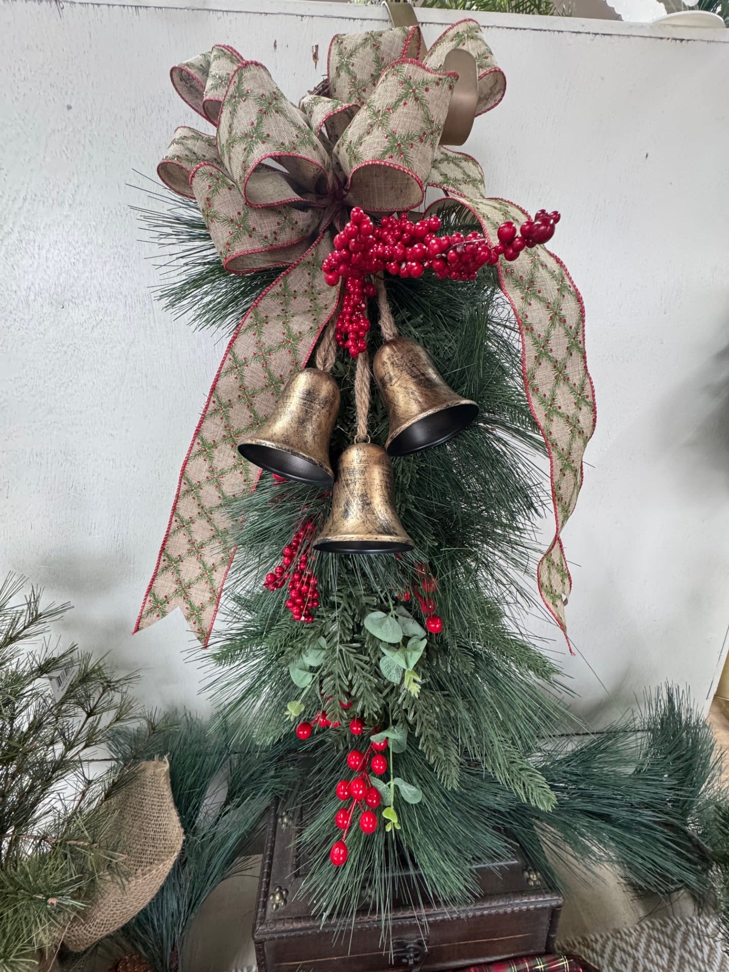 Jingle Berry Holiday Silk Swag - Bring festive cheer to your home with the Jingle Berry Holiday Swag, a charming blend of classic holiday elements and rustic winter warmth. This handcrafted faux greenery swag features vibrant red berries, delicate winter greens, and decorative bells that add a soft, joyful jingle with every movement. Accented with a beautifully coordinated brown, green, and red bow, it offers the perfect balance of color and texture for the season.  Designed for doors, mantels, entryways, or stair rails, this long-lasting piece captures the nostalgic spirit of Christmas while requiring no upkeep. Let the Jingle Berry Holiday Swag welcome guests with timeless holiday charm all season long.