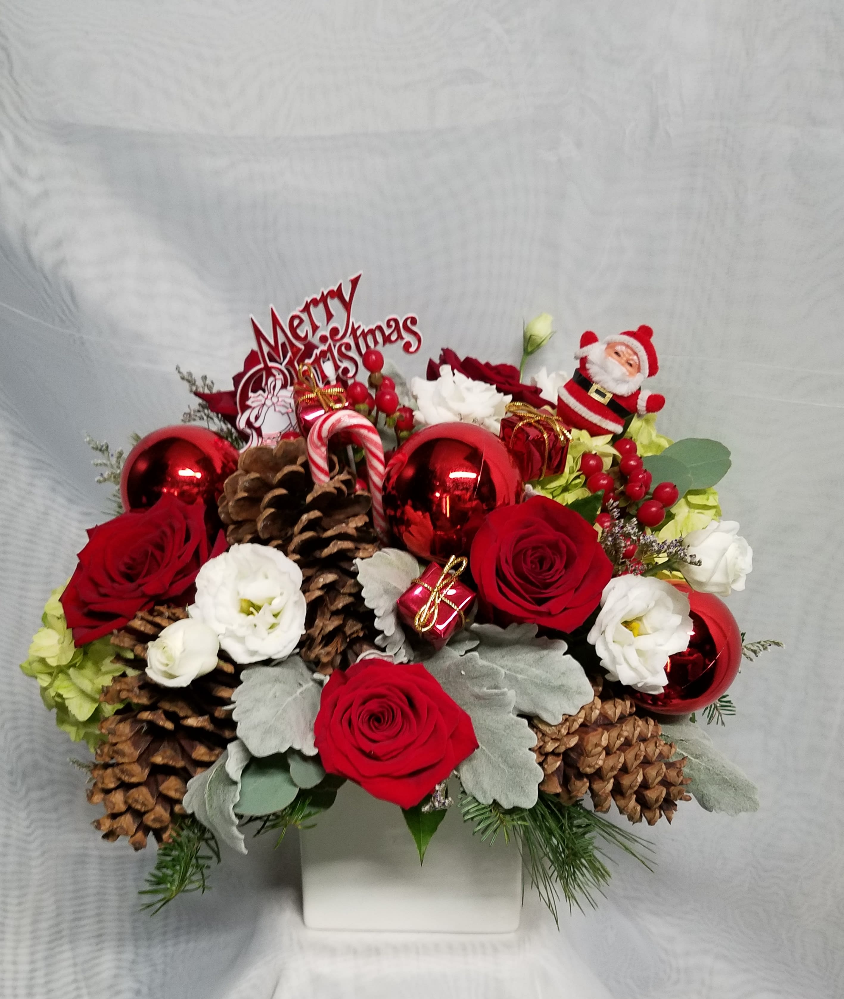 christmas spirit  - A beautiful arrangement for christmas whit red roses,  pinecones, green hydrengea, white licianthus, dusty miller, red berrys and christmas ornaments 