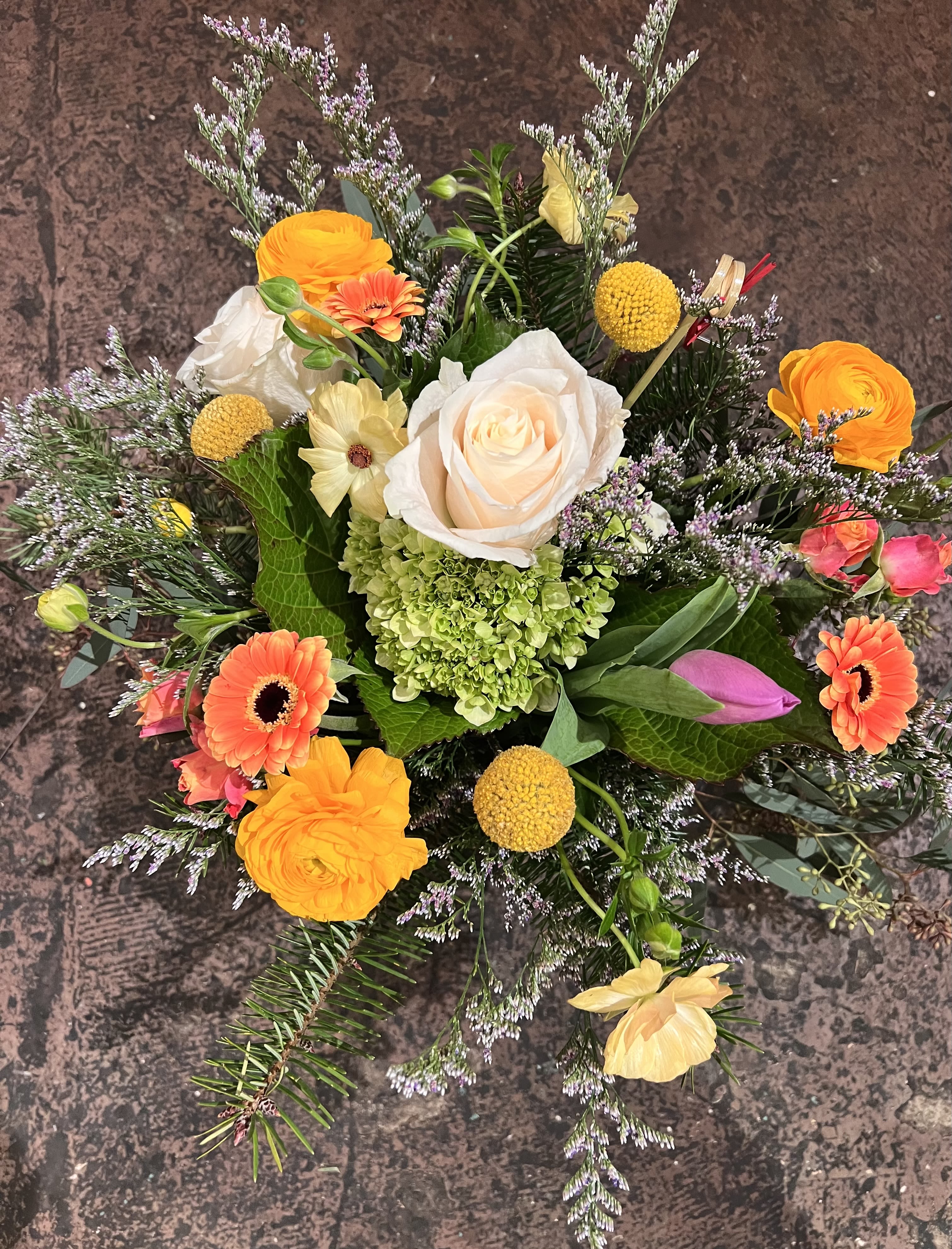 Golden Meadow - Featuring premium ivory roses, bold orange blooms, golden billy balls, and vibrant hydrangea, this modern arrangement bursts with fresh, uplifting color. Textured greenery and lilac-toned fillers complete the look with effortless elegance.