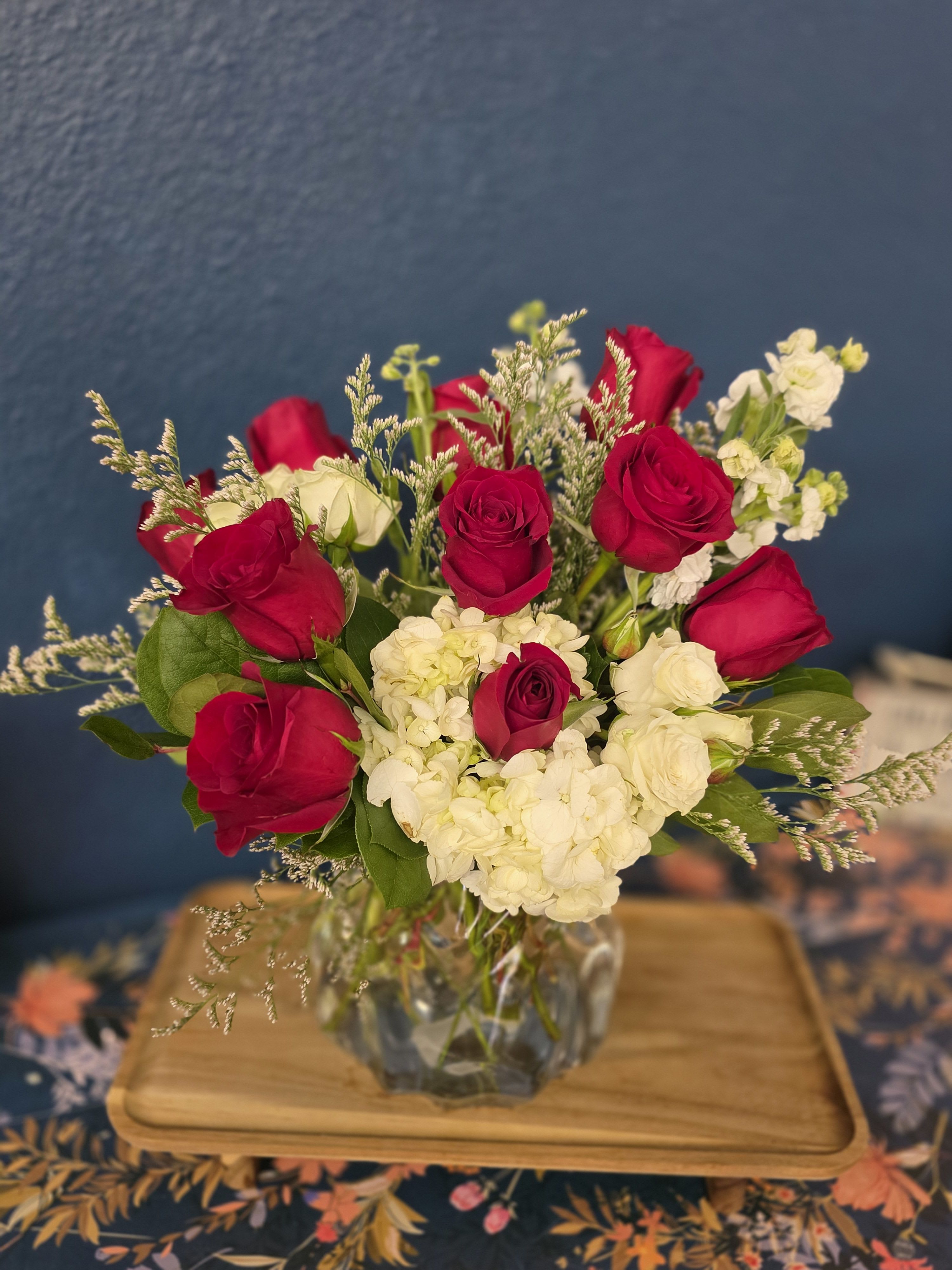 Lovely Laurette - Red roses, hydrangea, spray roses and greenery designed in a gorgeous crystal style vase. Great for the Christmas season, Valentine's Day or to celebrate an Anniversary.   Standard size includes a half dozen roses. Deluxe size includes 9 roses. Premium size includes a full dozen. *photo is a premium design 