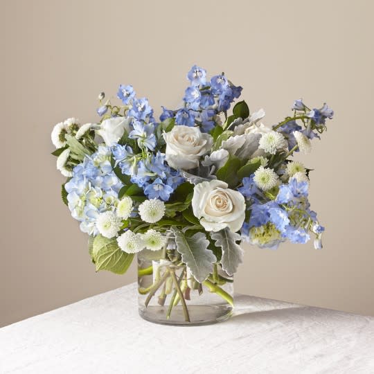 Clear Skies Bouquet - Let this uplifting arrangement be reminders of the clear skies ahead. Capturing the feeling of hope that a new day brings, this bouquet is composed of voluminous hydrangea blooms and vibrant belladonna delphinium to refresh their mood.  Please Note: The bouquet pictured reflects our original design for this product. While we always try to follow the color palette, we may replace stems to deliver the freshest bouquet possible, and we may sometimes need to use a different vase.  The Premium Bouquet is approximately 19&quot;H x 24&quot;W.