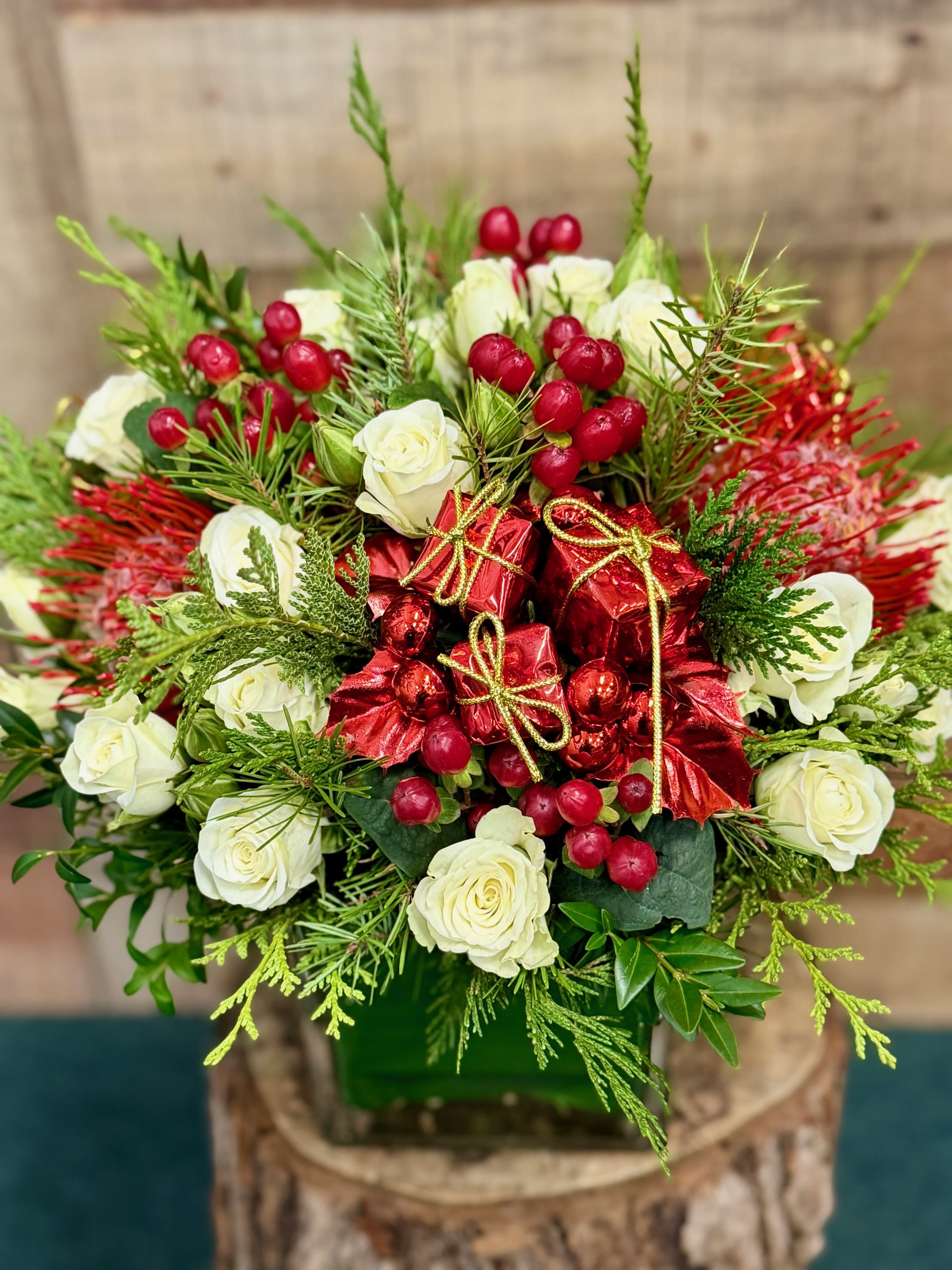 Winter Berry Rose - Snow white spray roses, tropical protea and festive holiday greens accented with red berries makes a cheerful holiday gift.
