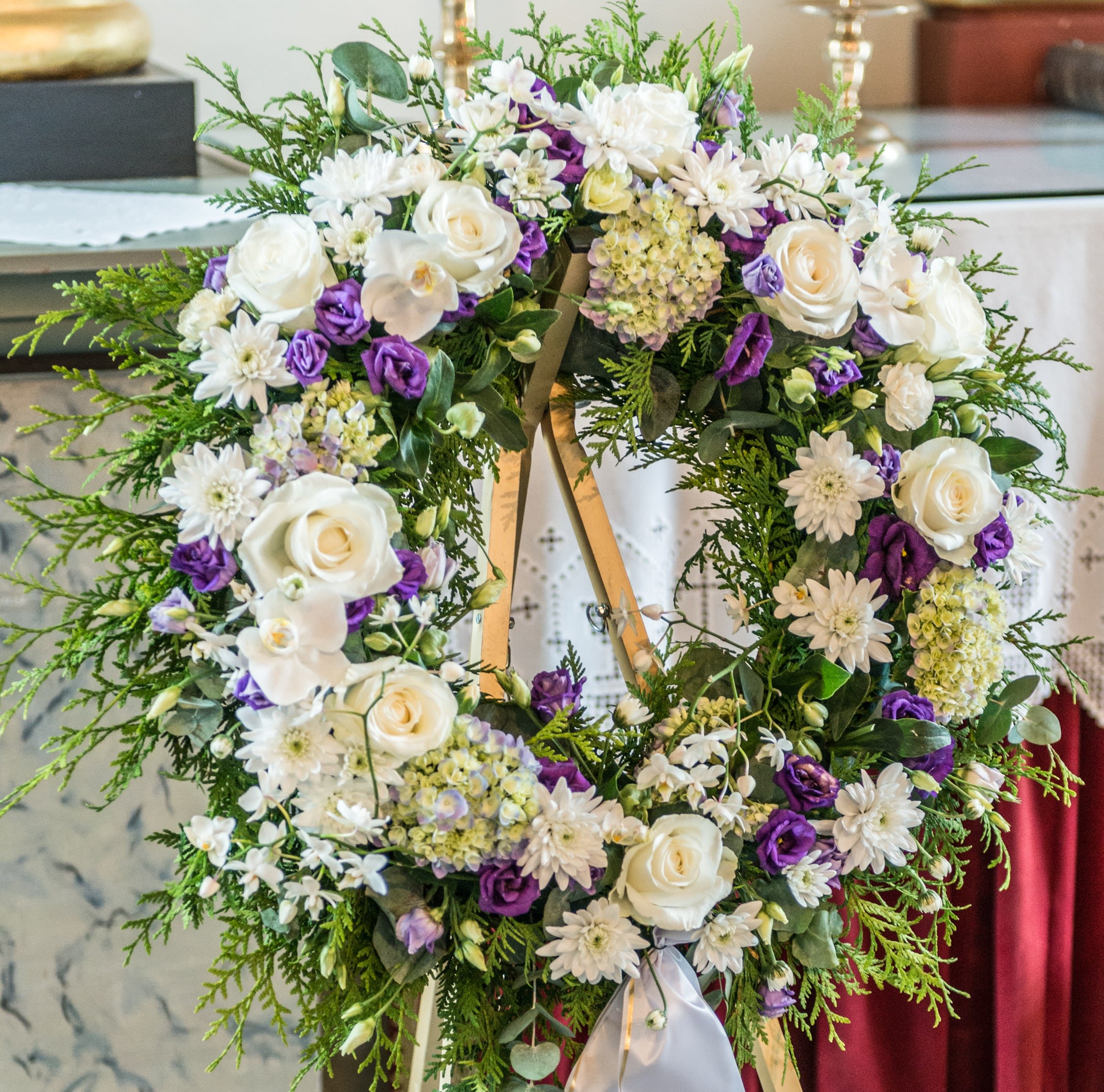 A Life Remembered - A beautiful white and purple tribute wreath that calms, this arrangement celebrates a full life and a peaceful passing. (Easel Not Included)