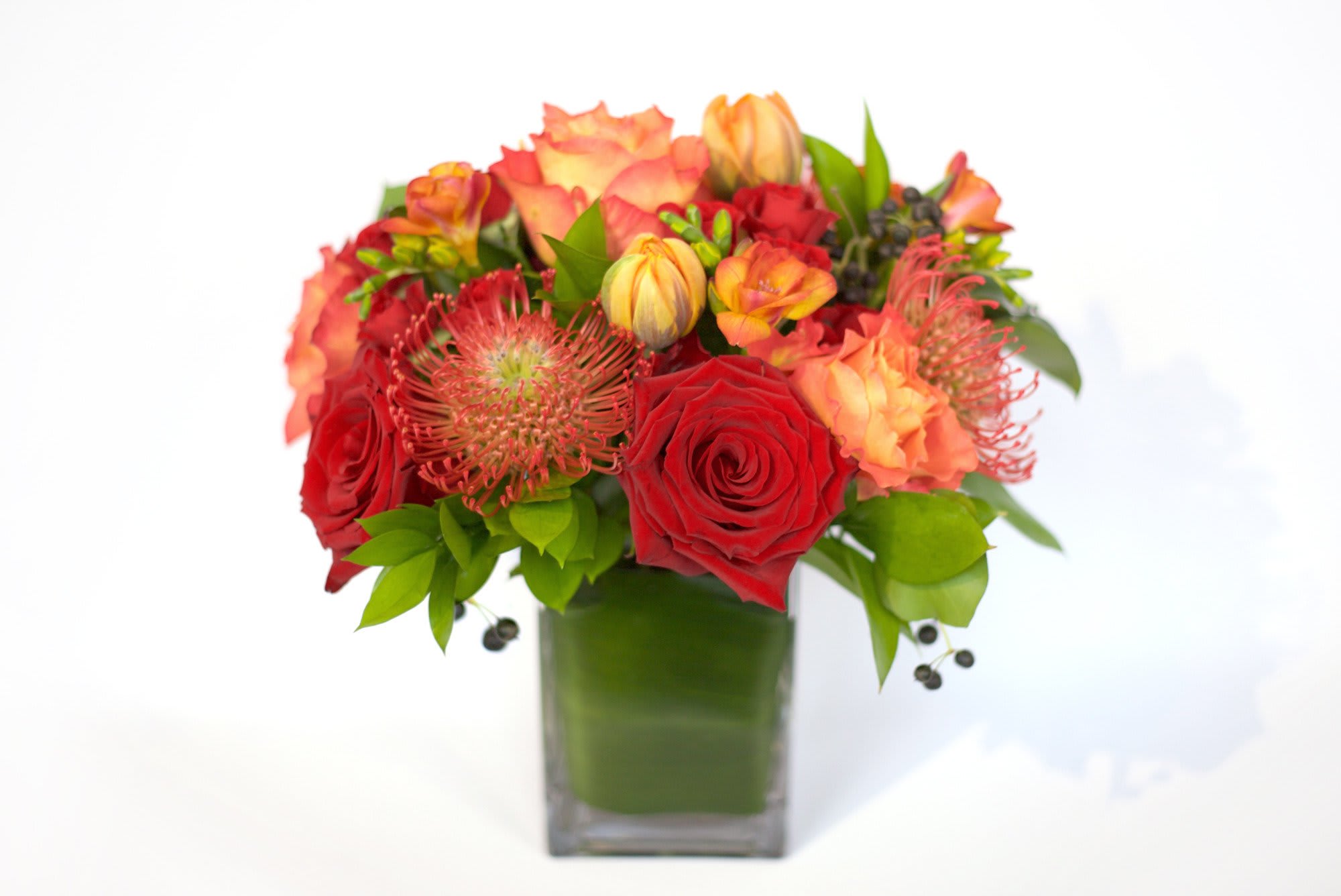 Fiery Reds &amp; Oranges - Red and orange blooms arranged together for an expression of energy, enthusiasm, and boldness.  This arrangement features seasonal blooms, statement flowers, and textured greens in these strong colors.