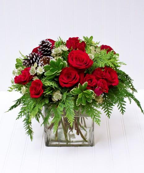 christmas gift - cube with red green and white flowers arranged with pine cones 