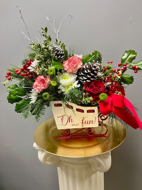 SLEIGH BELLS - Sleigh Bells is designed in a charming white sleigh filled with winter greens, red and white flowers, berries and pinecones. The sleigh can be refilled for years to come. 