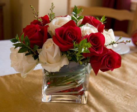 Christmas Rose Arrangement - An elegant arrangement in a clear glass cube with Red &amp; White Roses and seasonal foliage.