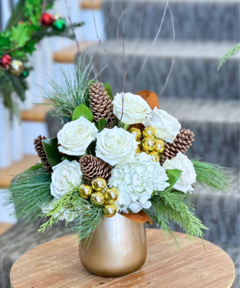 Winter Glow Bouquet - WINTER COLLECTION | LOCAL DELIVERY ONLY  Bring a touch of elegance to the season with this stunning winter arrangement, designed in a sleek gold vase. Featuring white hydrangea and roses, natural pinecones and branches, mixed winter greenery, and sparkling gold accents, including mini ornaments, it radiates warmth, light, and festive charm.