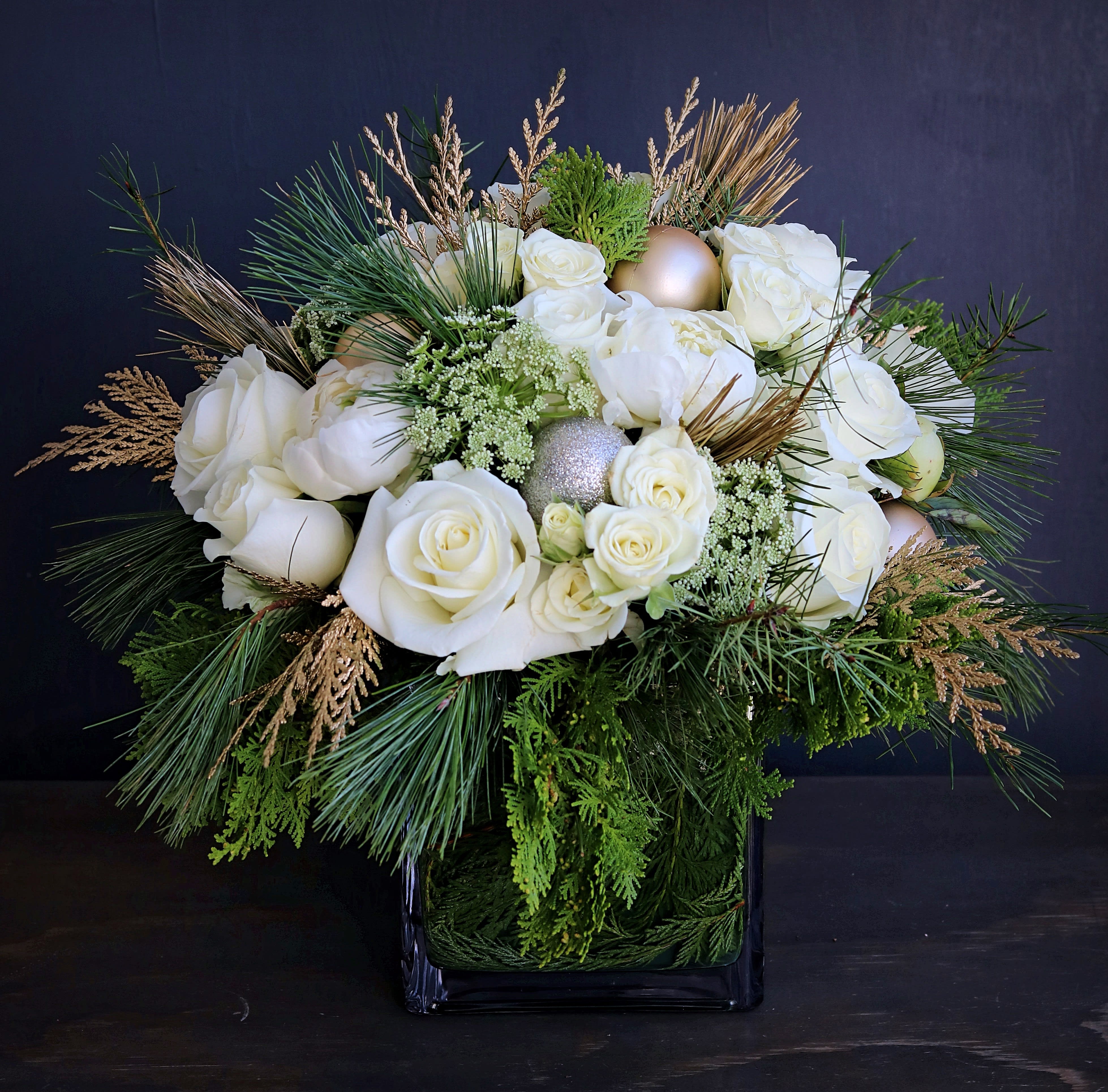 white christmas centerpiece - Mixed white blooms such as roses, spray roses and peonies with Christmas greens and gold ornaments in 6" square glass vase. Our specialty designed greeting card with a handwritten message is included. Send the most beautiful flowers for that special someone. Next day delivery available to Tequesta, Jupiter, Palm Beach Gardens and Palm Beach.
