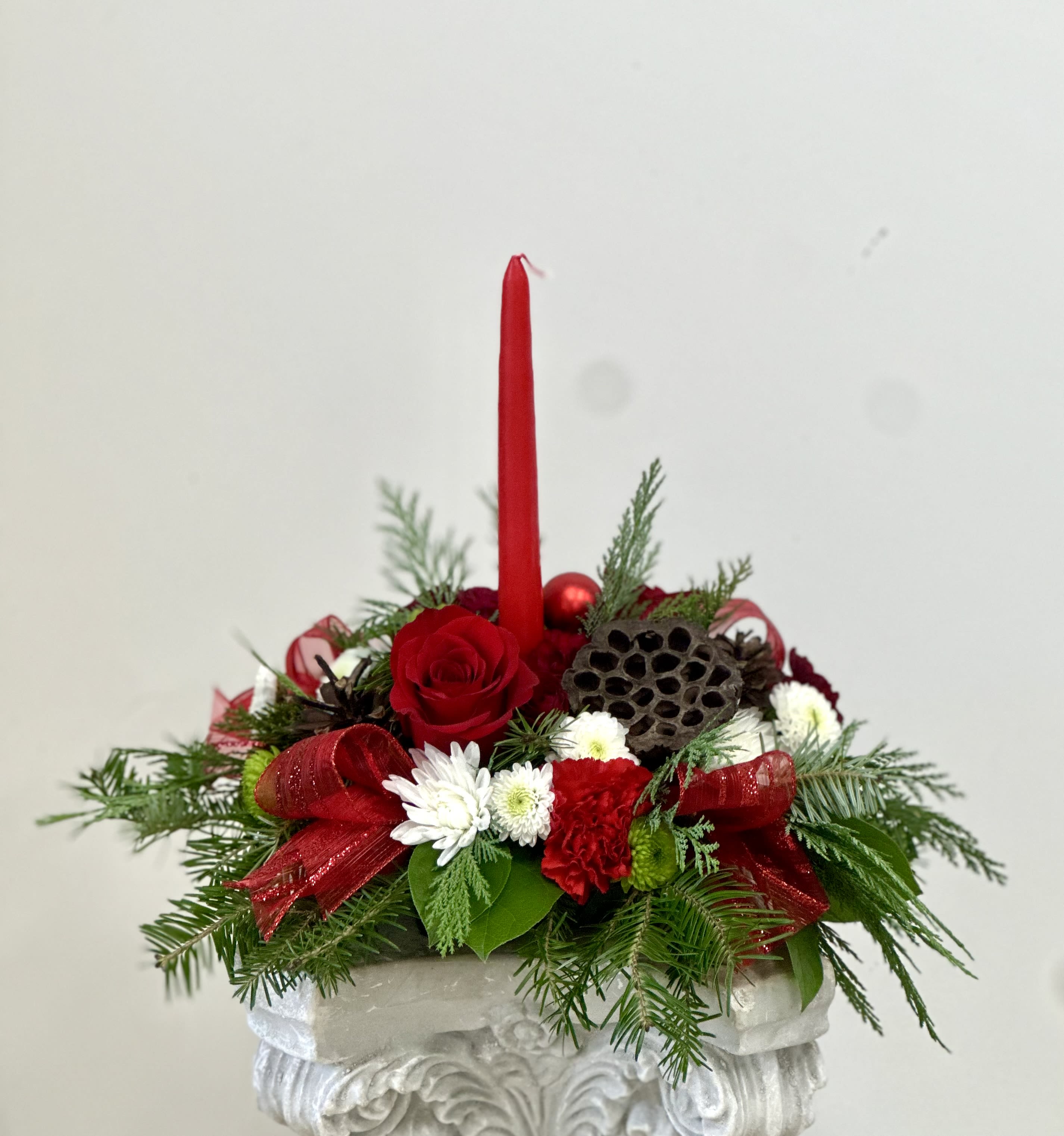 Evergreen Candlelight Centerpiece by Westford Florist - Elevate your holiday celebrations with the Evergreen Candlelight Centerpiece by Westford Florist. This stunning arrangement features lush evergreen branches artfully intertwined with soft, flickering candlelight, creating an inviting ambiance that transforms any gathering into a memorable occasion. Perfectly suited for intimate dinners or festive feasts, this centerpiece not only enhances your table but also captures the essence of the season. Delight in its beauty and let it brighten your home throughout the holidays. Make every meal a celebration with this exquisite touch of nature’s elegance.