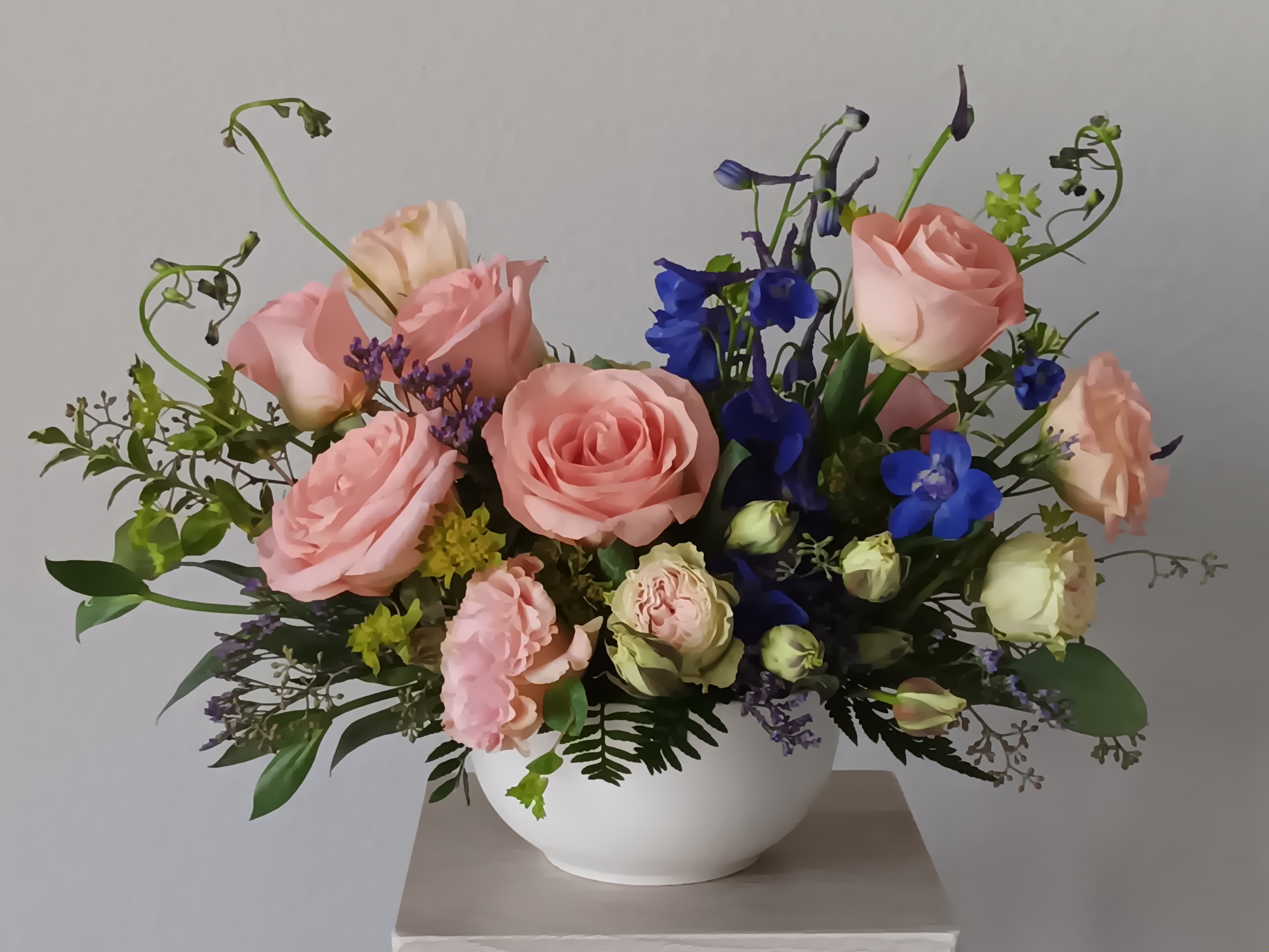 Arrive in Style Bouquet - Express your love with the eloquence of Shakespeare - without saying a word. She'll adore this exquisite bouquet of roses and other pastel and blue favorites in a classic ciramic cvase. And she'll know just the words to let you know. Light pink roses, pink lisiantis, bliue delphinium and pink cushion spray chrysanthemums are mixed with white statice and variegated pittosporum in a ciramic, rounded vase. Orientation: All-Around  SUBSTITUTION POLICY – Always deliver the freshest flowers! Please note the bouquet pictured reflects our original design.  If the exact flowers or container in this arrangement are not available, our local florists will create a beautiful bouquet with the freshest available flowers.