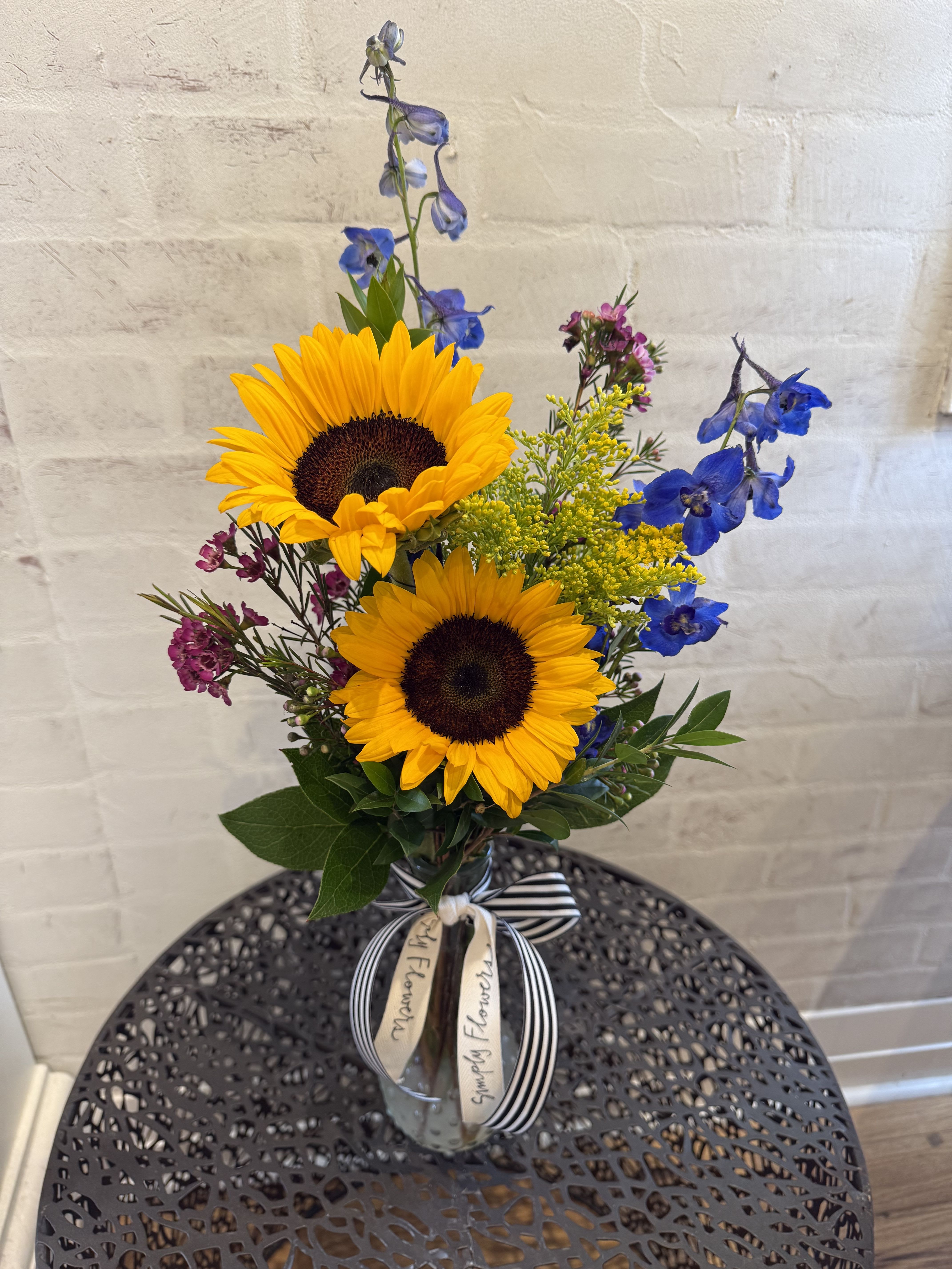 A Little Pick Me Up - This will be a designer choice. We will create a beautiful arrangement using our fresh, in house product. Photo is an example. Will be designed in a linear fashion, taller in a glass bud vase. 