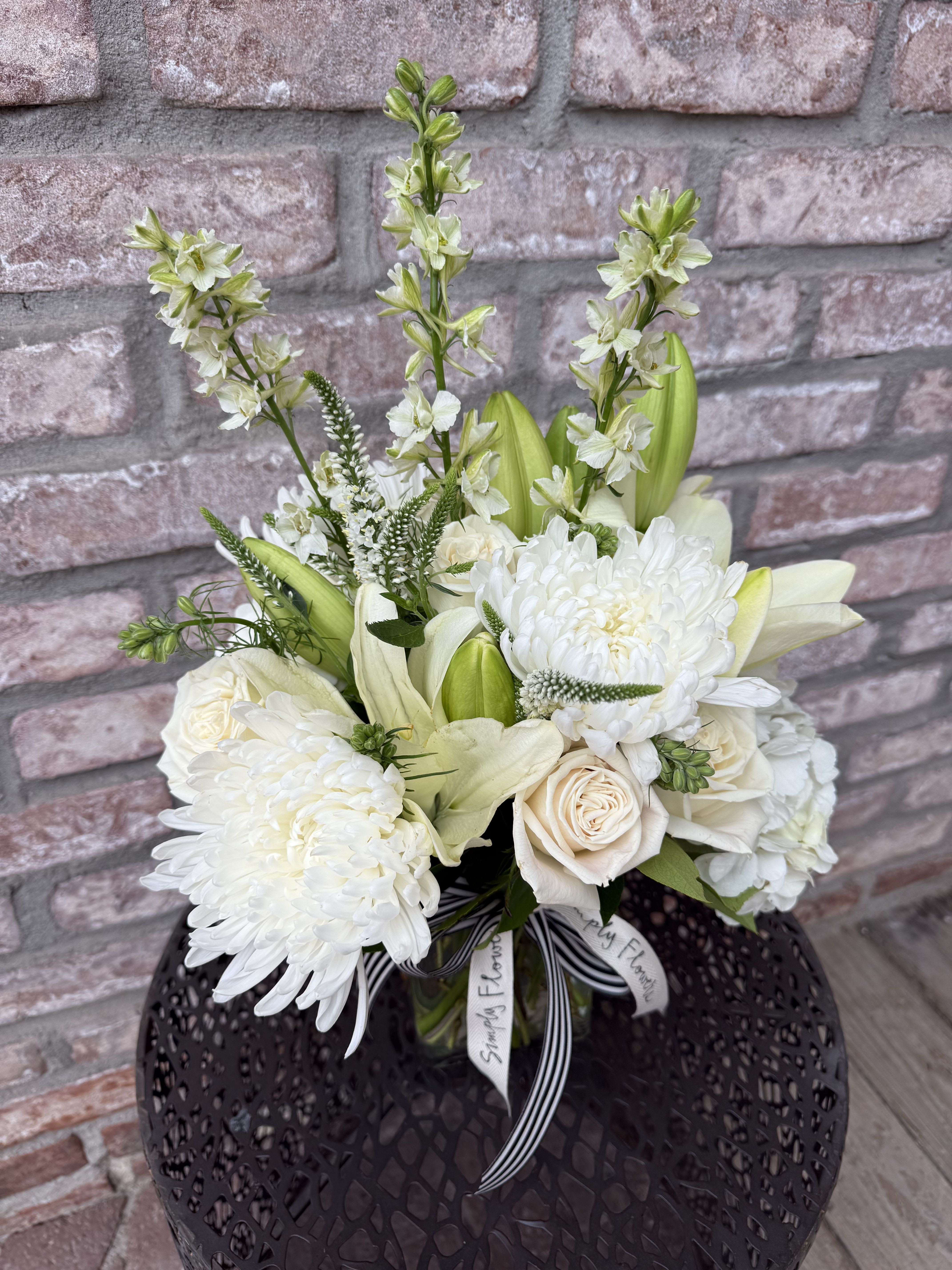 Stay Classy - A lush arrangement all dressed in white. Designed in a glass rectangular vase. Filled with fresh lilies, hydrangeas, freesia, ranunculus and snapdragon. 