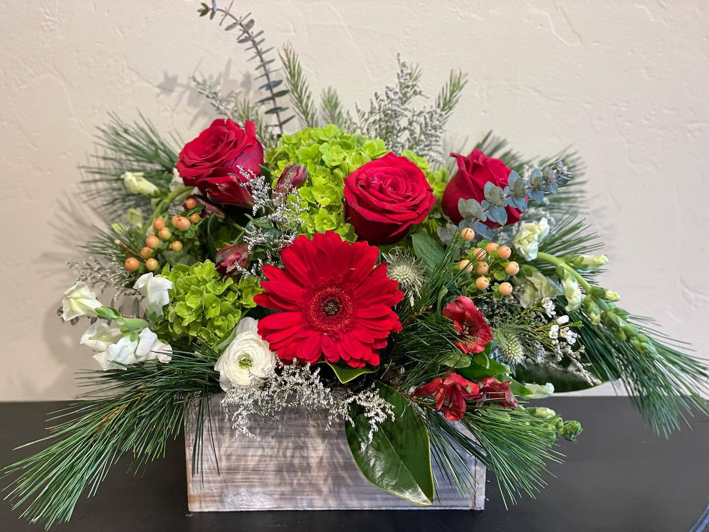 Holiday Cheer  - A Designer’s Choice wooden box arrangement filled with a variety of blooms! This is the perfect way to enjoy the colors, textures, and variety of the Season. Flowers and colors WILL VARY so no two will ever be alike, rest assured it will reflect the holiday season! 