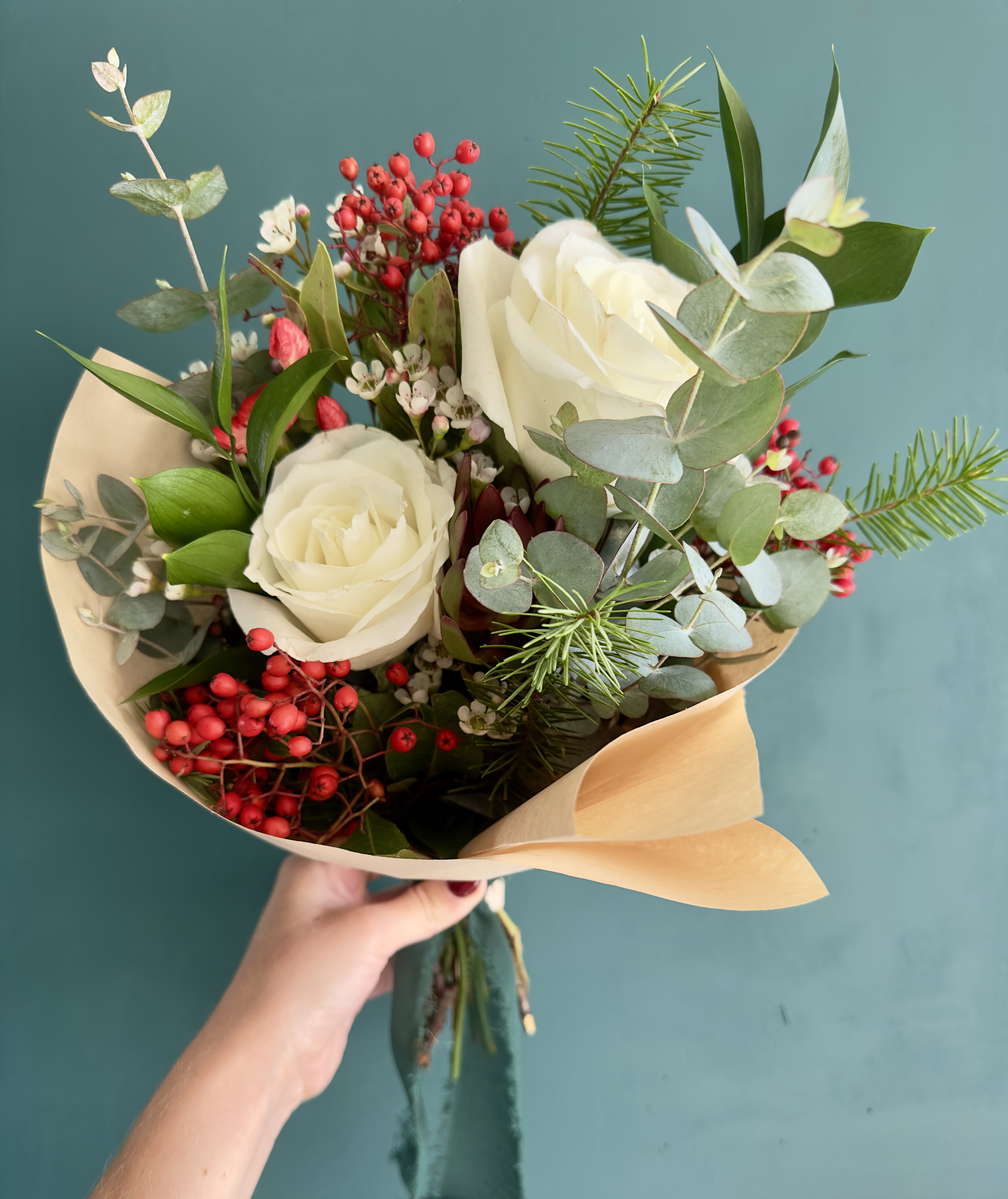 Winter Garden Holiday Hand-Tied Bouquet - Celebrate the beauty of the season with our Winter Garden Holiday Hand-Tied Bouquet, Celebrate the beauty of the season with our Winter Garden Holiday Hand-Tied Bouquet, thoughtfully designed to feel timeless, cozy, and effortlessly elegant.  This hand-tied arrangement features creamy white roses nestled among seasonal winter greenery, eucalyptus, festive red berry accents, and textural evergreen touches. Each bouquet is wrapped in natural kraft paper and finished with a soft ribbon, creating a refined yet organic holiday look that feels both elevated and inviting.  Designed to be placed in your own vase or gifted just as it is, this bouquet is perfect for holiday hosting, winter celebrations, seasonal gifting, or simply bringing warmth and beauty into your home. Every bouquet is handcrafted in our La Mesa floral studio using thoughtfully sourced blooms, making each one unique.  Whether you’re gifting someone special or treating yourself, this bouquet is a beautiful reminder that small moments of beauty matter—especially during the holidays.  Details: • Hand-tied bouquet (vase not included) • Features white roses, winter greenery, eucalyptus, and seasonal accents • Wrapped in kraft paper with ribbon • Designed for holiday gifting and winter décor • Florist’s seasonal selection may vary slightly for freshness and quality thoughtfully designed to feel timeless, cozy, and effortlessly elegant.