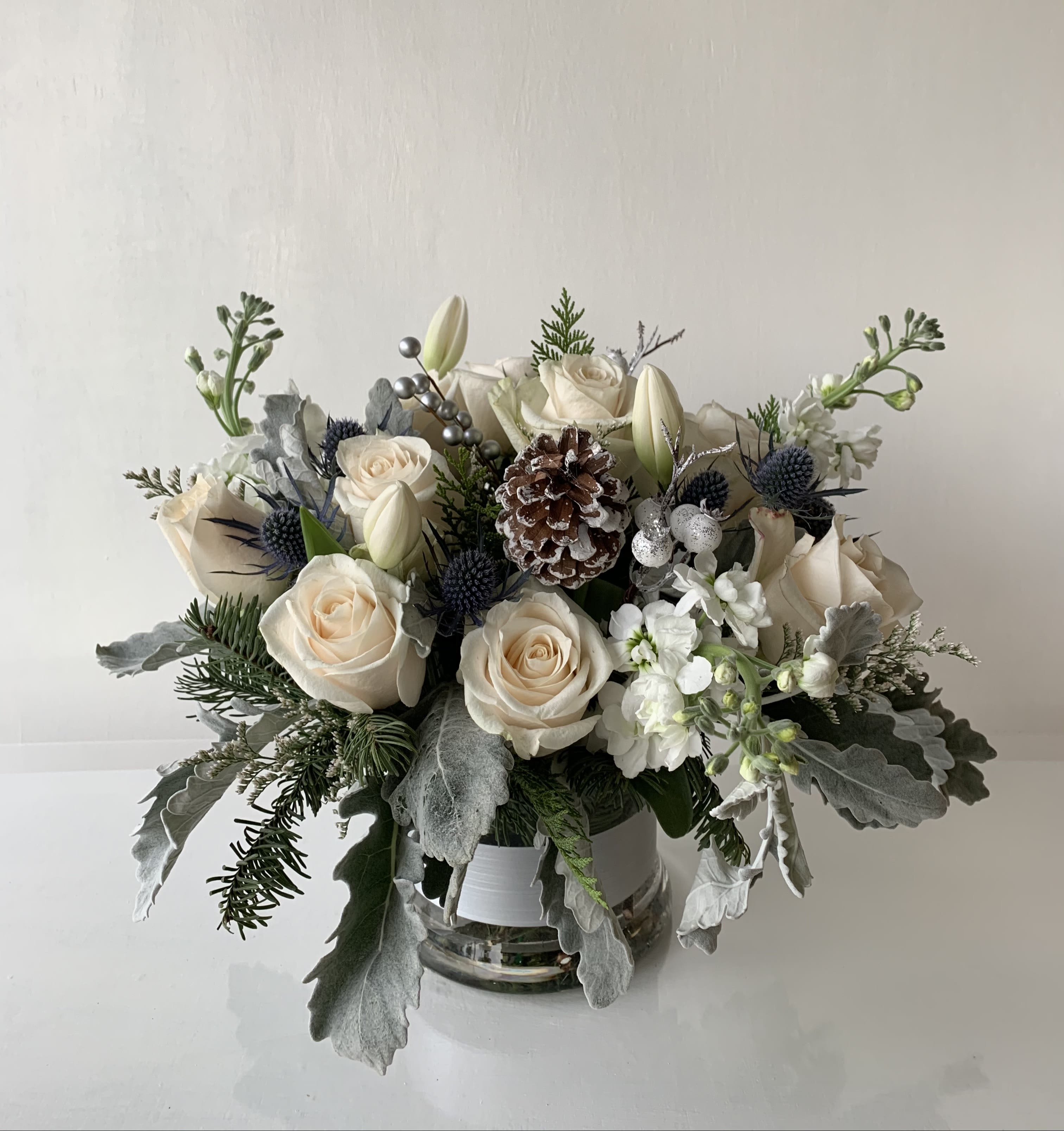 Christmas Morning - An arrangement of white rose, tulip, and stock in a 5" cylinder vase. This will be the focal point at your dinner table.