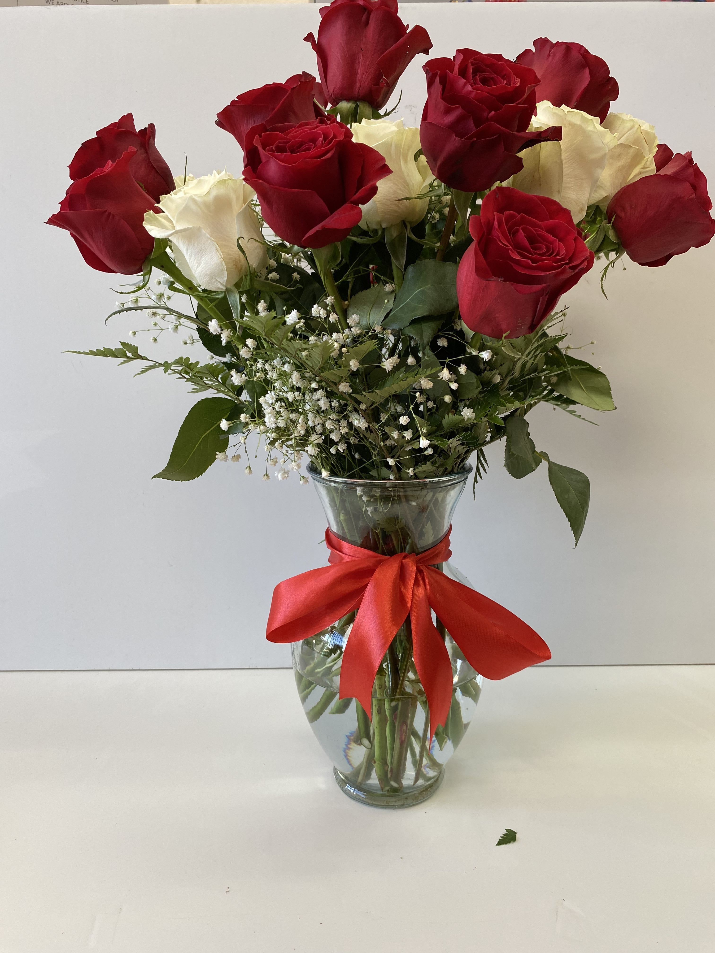 Red and White Splendor  - Splendid 12 red roses and  6 white roses, baby breath and  Greenery leatherleaf ; in a clear vase with a outstanding bow ribbon. 